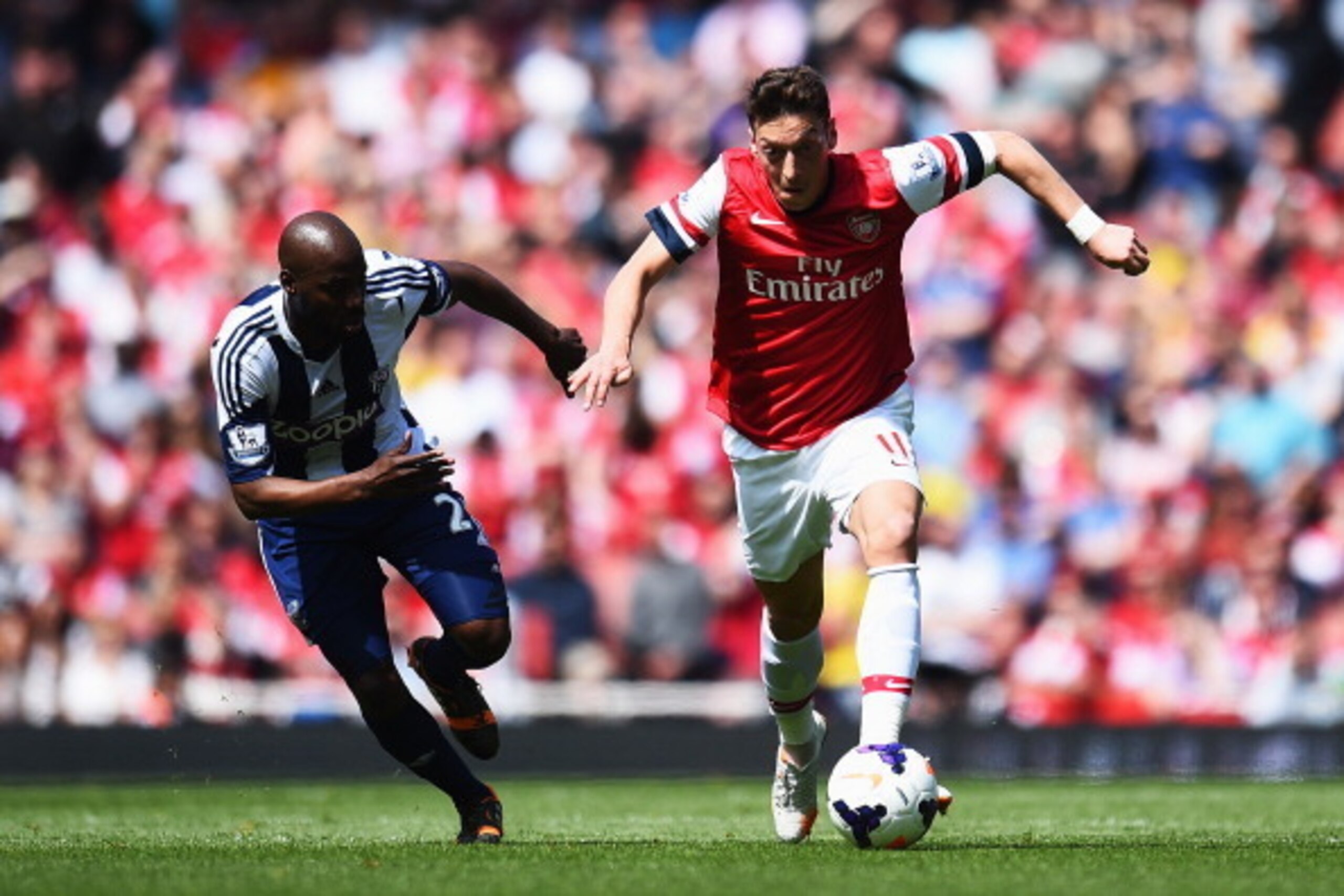 LONDON, ENGLAND - MAY 04:  Mesut Ozil (R) of Arsenal holds off the challenge of Youssuf Mulumbu (L) of West Bromwich Albion during the Barclays Premier League match between Arsenal and West Bromwich Albion at the Emirates Stadium on May 4, 2014 in London,