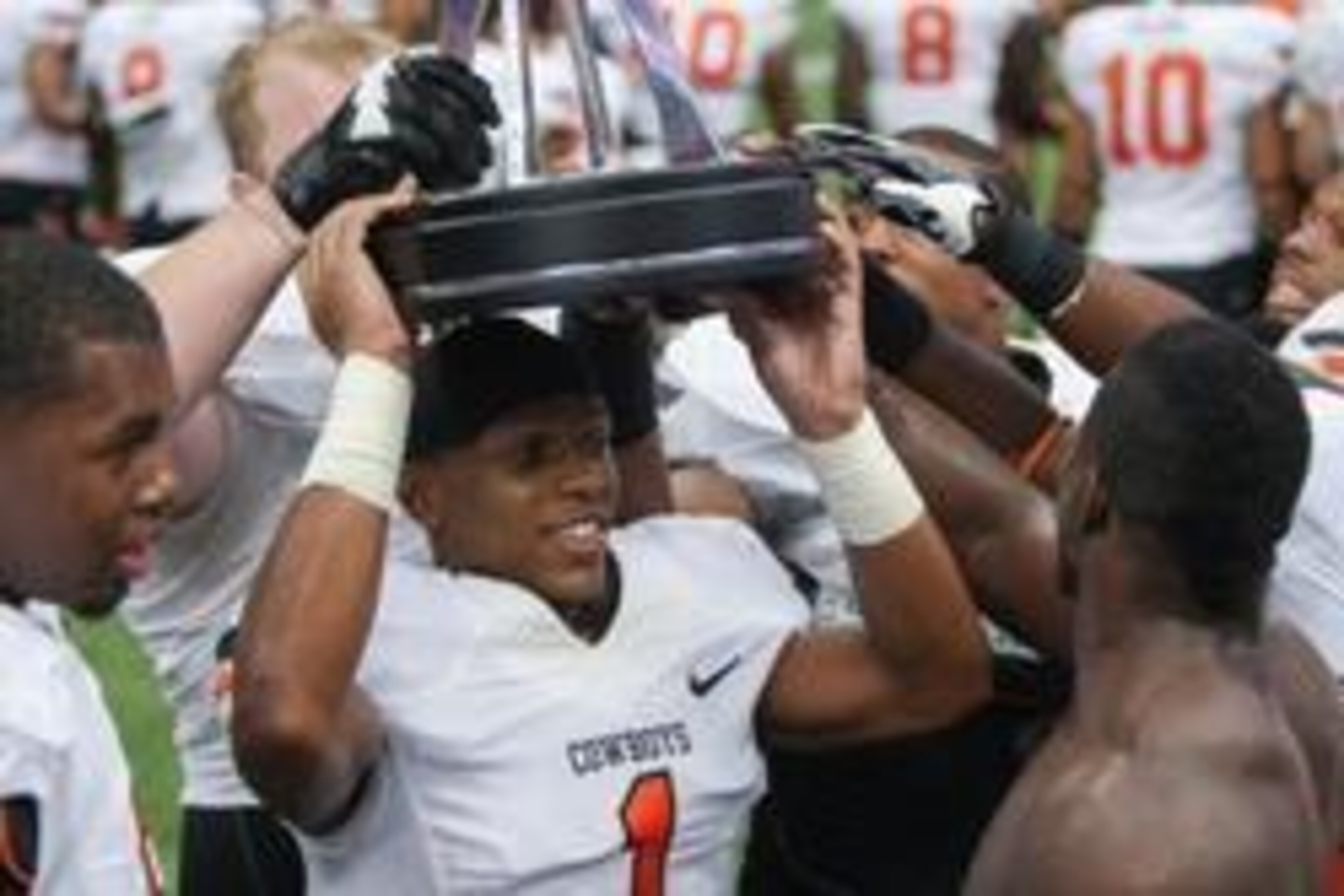 Aug 31, 2013; Houston, TX, USA; Members of the Oklahoma State Cowboys including Kevin Peterson (center) hold a trophy after defeating the Mississippi State Bulldogs at Reliant Stadium. Mandatory Credit: Troy Taormina-USA TODAY Sports