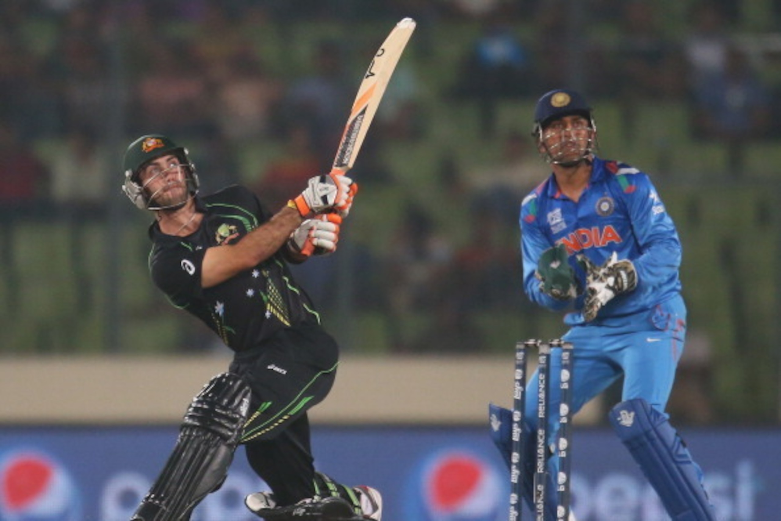 DHAKA, BANGLADESH - MARCH 30:  Glenn Maxwell of Australia hits a six as MS Dhoni of India looks on during the ICC World Twenty20 Bangladesh 2014 match between India v Australia at Sher-e-Bangla Mirpur Stadium on March 30, 2014 in Dhaka, Bangladesh.  (Phot