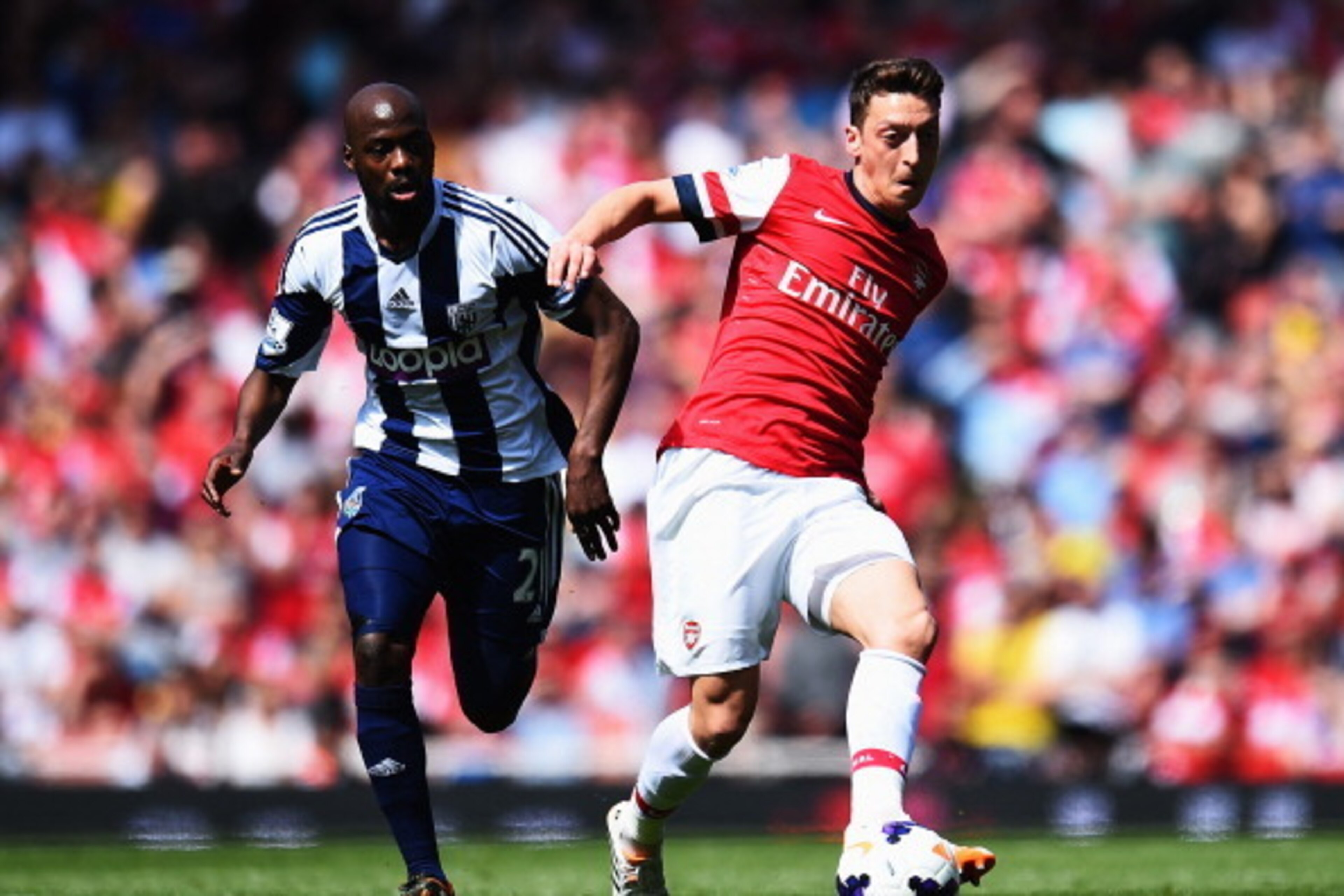 LONDON, ENGLAND - MAY 04:  Mesut Ozil (R) of Arsenal controls the ball ahead of Youssuf Mulumbu (L) of West Bromwich Albion during the Barclays Premier League match between Arsenal and West Bromwich Albion at the Emirates Stadium on May 4, 2014 in London,