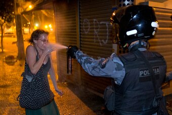 A protester in Rio de Janeiro is doused with tear gas by a member of the Brazilian police.