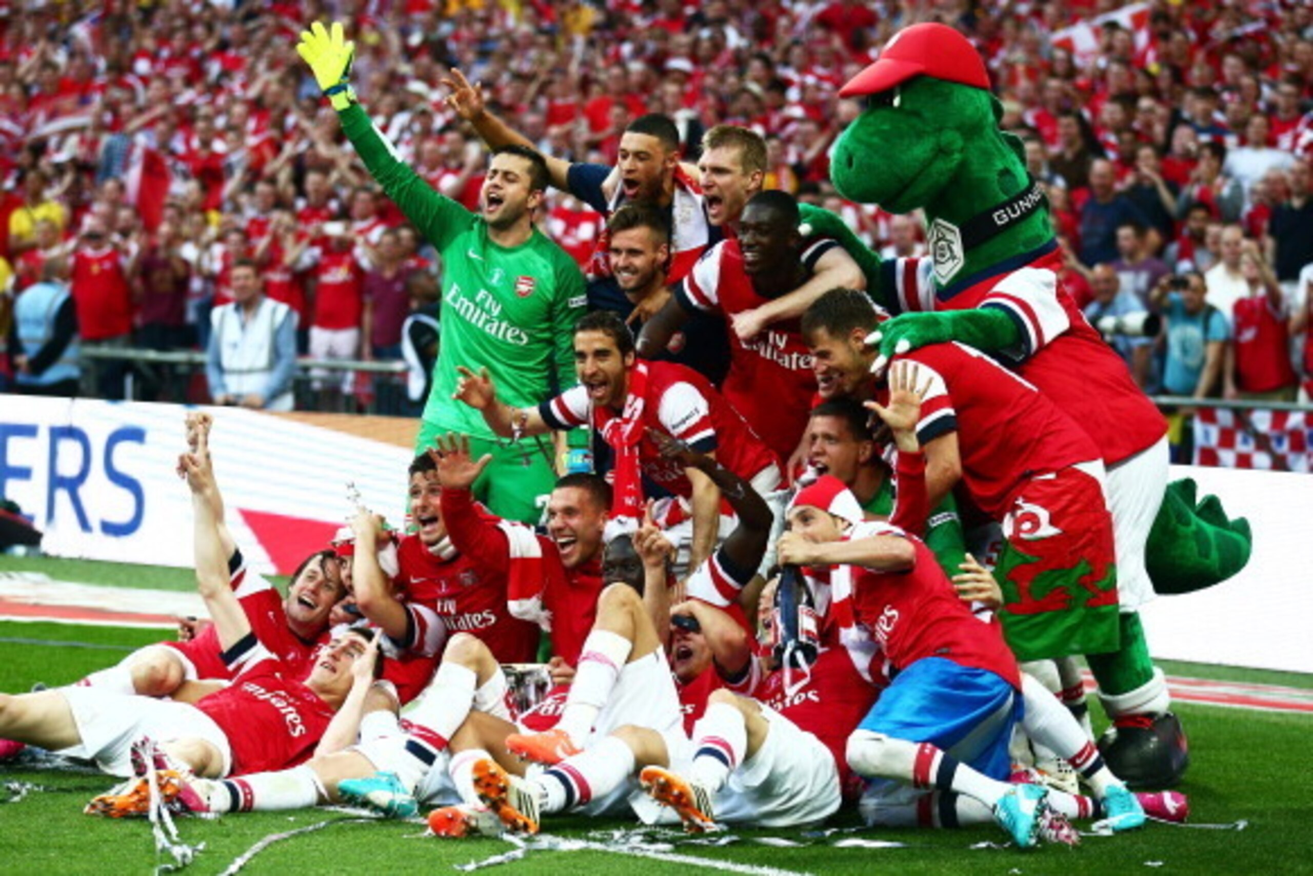 LONDON, ENGLAND - MAY 17:  Arsenal players celebrate victory with mascot Gunnersauraus Rex after the FA Cup with Budweiser Final match between Arsenal and Hull City at Wembley Stadium on May 17, 2014 in London, England.  (Photo by Clive Mason/Getty Images