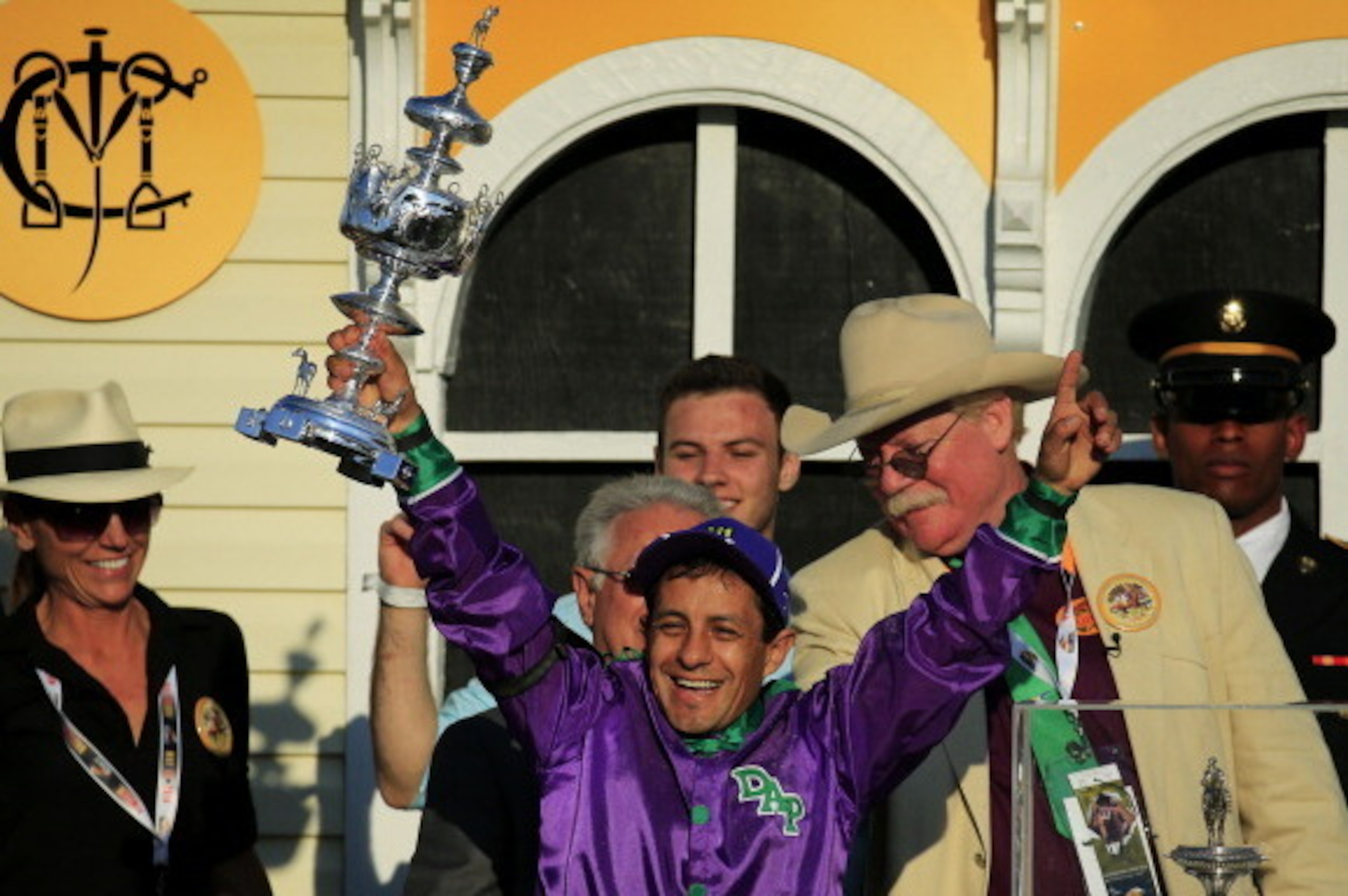 BALTIMORE, MD - MAY 17:  Owner of California Chrome Steve Coburn (R) celebrates in the winner's circle with jockey Victor Espinoza (C) after winning the 139th running of the Preakness Stakes at Pimlico Race Course on May 17, 2014 in Baltimore, Maryland.  