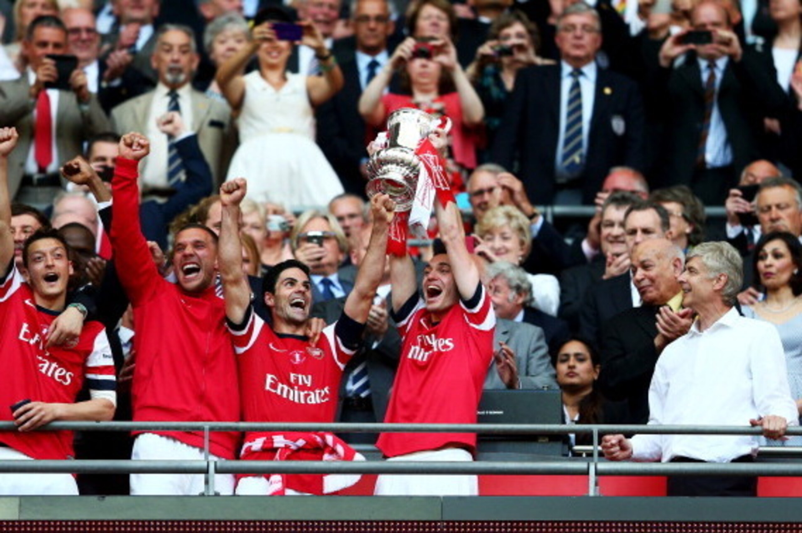 LONDON, ENGLAND - MAY 17:  Captain Thomas Vermaelen of Arsenal (2R) lifts the trophy in celebration as Arsene Wenger manager of Arsenal (R) looks on after the FA Cup with Budweiser Final match between Arsenal and Hull City at Wembley Stadium on May 17, 20
