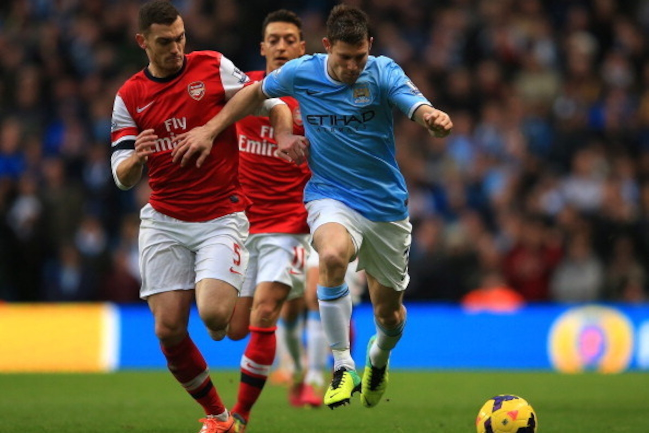 MANCHESTER, ENGLAND - DECEMBER 14: James Milner of Manchester City and Thomas Vermaelen of Arsenal compete for the ball during the Barclays Premier League match between Manchester City and Arsenal at Etihad Stadium on December 14, 2013 in Manchester, Engl