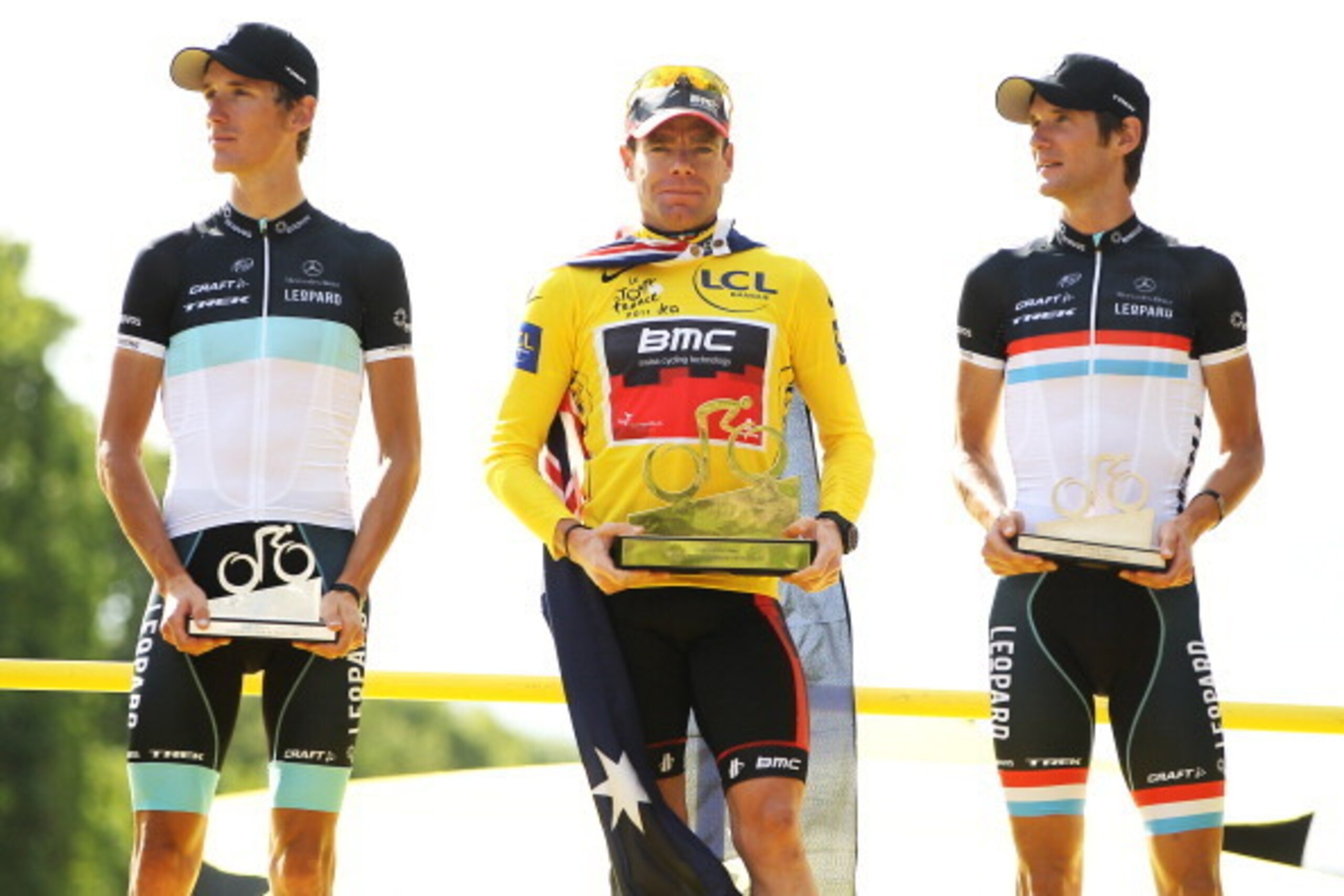 PARIS, FRANCE - JULY 24:  Yellow Jersey winner Cadel Evans (C) of team BMC celebrates with Andy Schleck (L) and Frank Schleck of team Leopard Trek on the podium after the twenty first and final stage of Le Tour de France 2011, from Creteil to the Champs-E