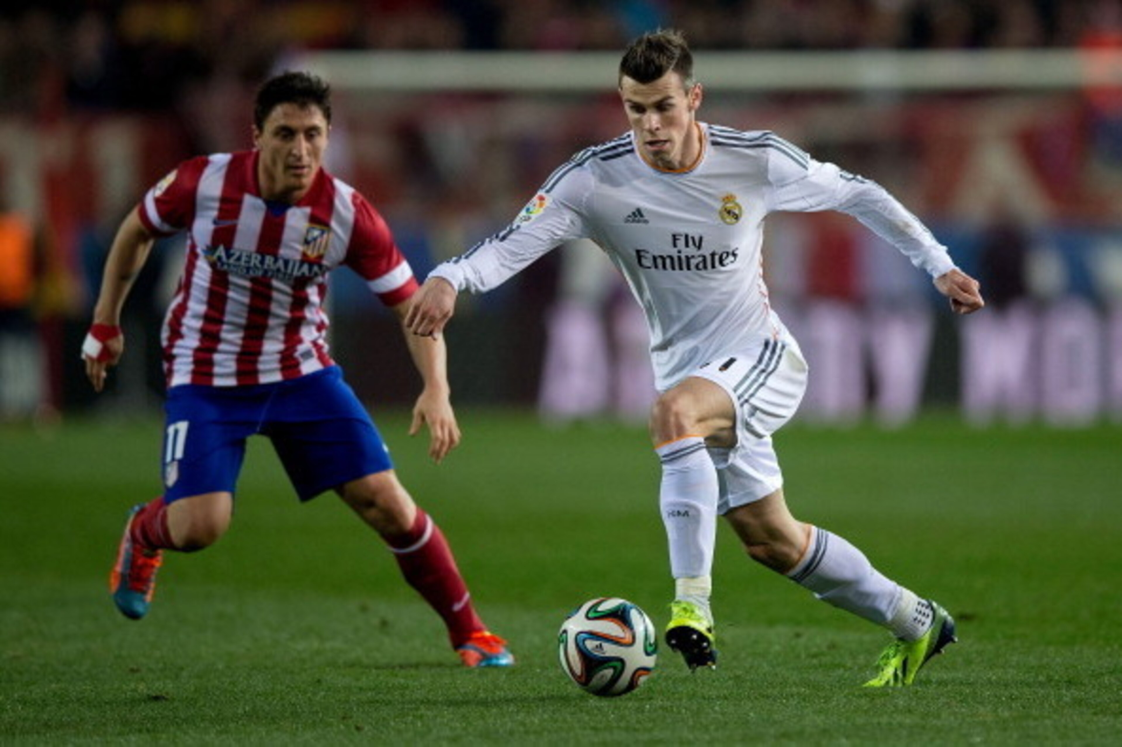 MADRID, SPAIN - FEBRUARY 11: Gareth Bale (R) of Real Madrid CF competes for the ball with Cristian Rodriguez alias El Cebolla (L) of Atletico de Madrid during the Copa del Rey semi-final second leg match between Club Atletico de Madrid and Real Madrid CF 