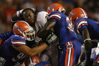 GAINESVILLE, FL - SEPTEMBER 06:  Running back Derron Thomas #21 of the Miami Hurricanes has his helmet knocked off his head as he is brought down by a gang tackle while taking on the Florida Gators at Ben Hill Griffin Stadium on September 6, 2008 in Gaine