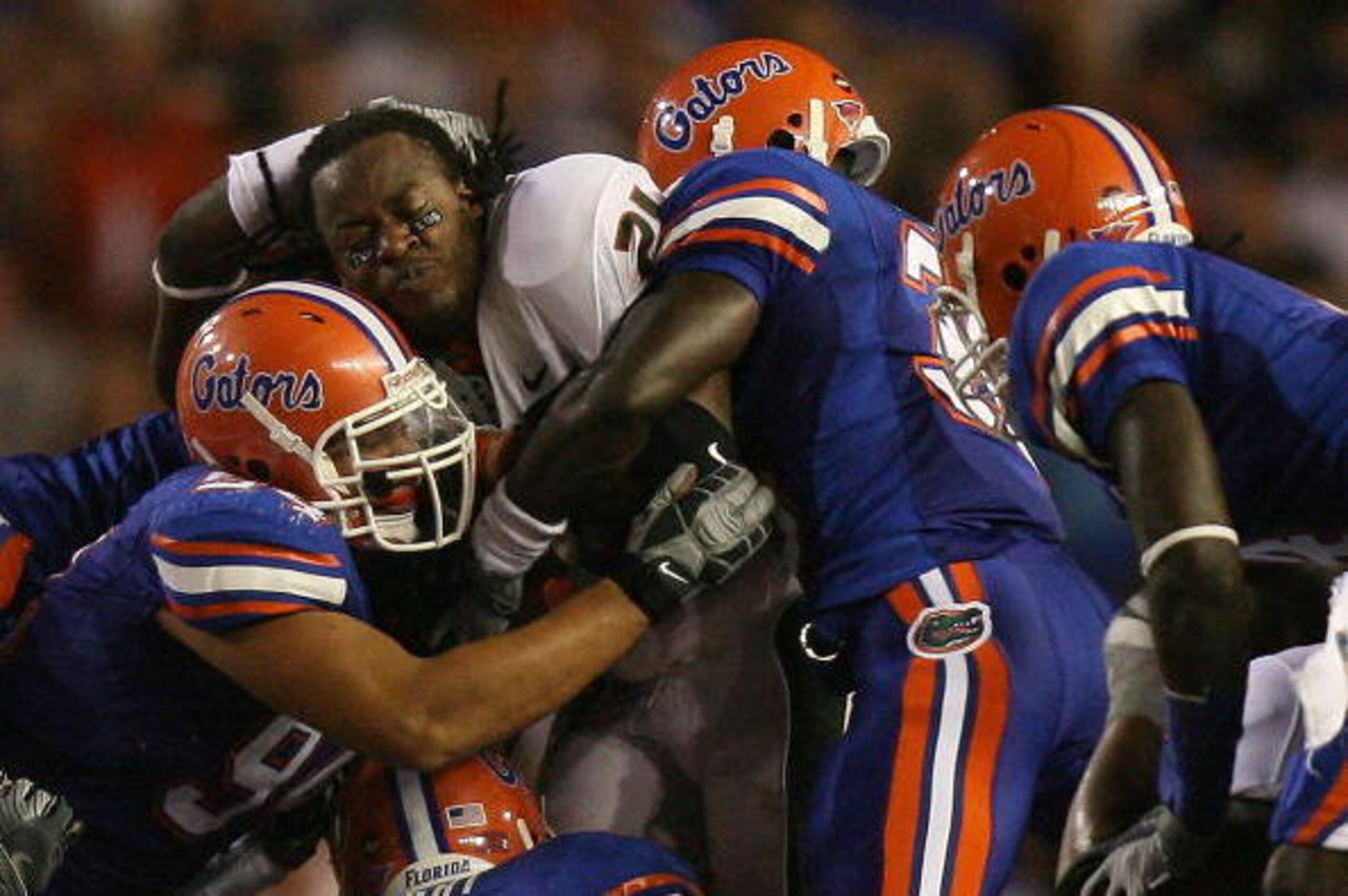 GAINESVILLE, FL - SEPTEMBER 06:  Running back Derron Thomas #21 of the Miami Hurricanes has his helmet knocked off his head as he is brought down by a gang tackle while taking on the Florida Gators at Ben Hill Griffin Stadium on September 6, 2008 in Gaine