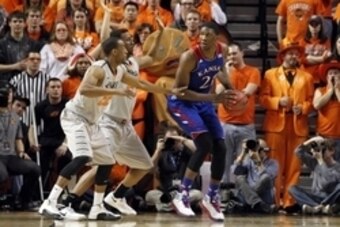 Mar 1, 2014; Stillwater, OK, USA; Kansas Jayhawks center Joel Embiid (21) is defended by Oklahoma State Cowboys forward/center Kamari Murphy (21) and guard Markel Brown (22) during the first half  at Gallagher-Iba Arena. Mandatory Credit: Tim Heitman-USA 
