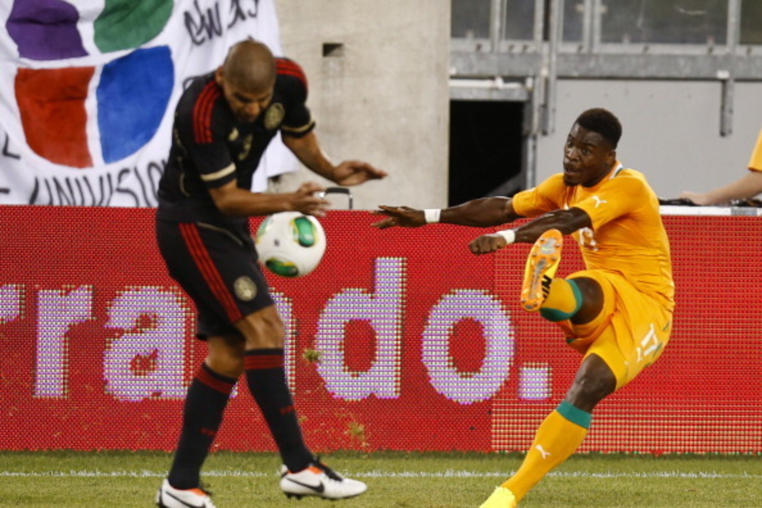 EAST RUTHERFORD, NJ - AUGUST 14:  Serge Aurier #17 of Ivory Coast kicks the ball into Carlos Salcido #3 of Mexico during their match at MetLife Stadium on August 14, 2013 in East Rutherford, New Jersey.  (Photo by Jeff Zelevansky/Getty Images)