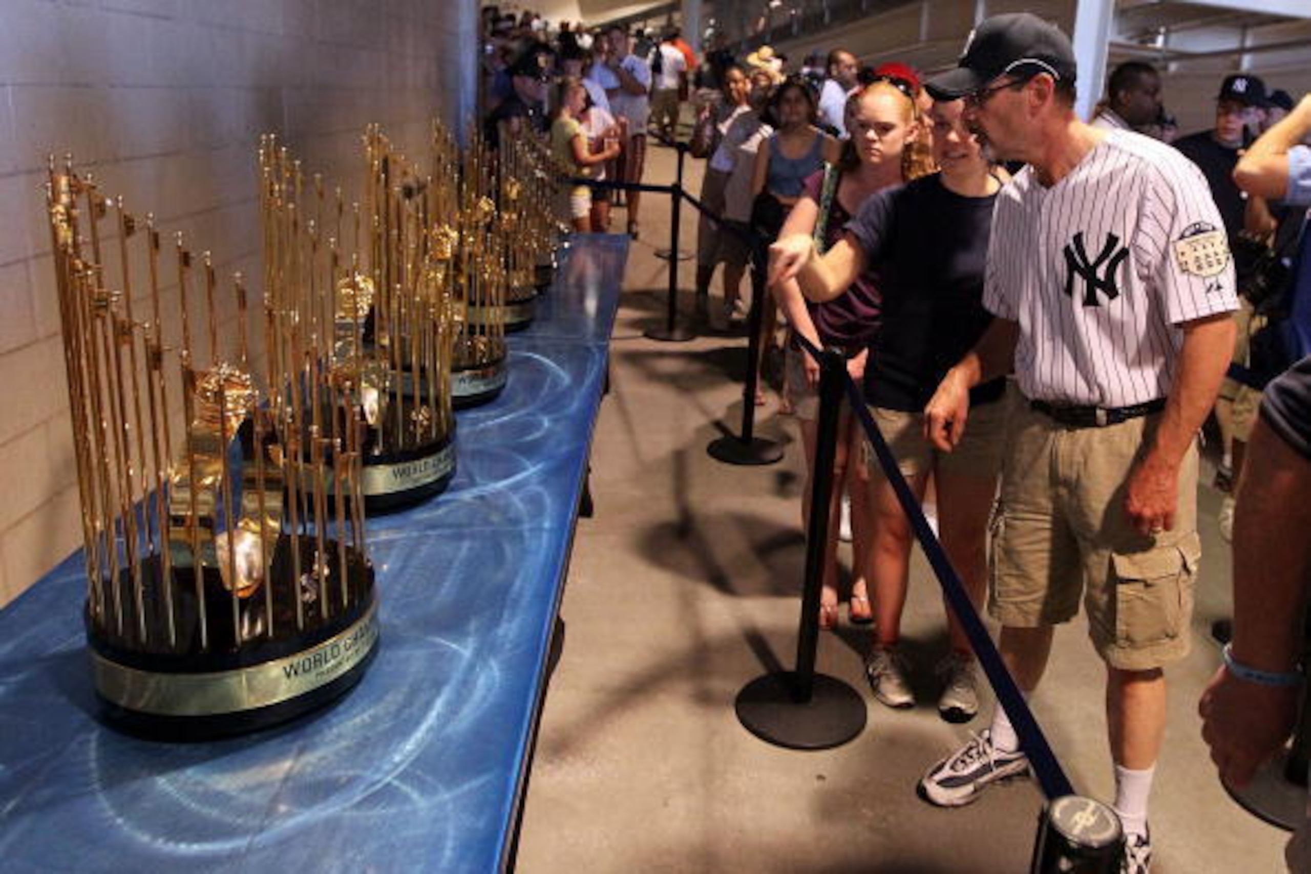 NEW YORK - JULY 04:  Fans view the seven World Series championship trophies won by the New York Yankees under the ownership of George Steinbrenner prior to the game against the Toronto Blue Jays on July 4, 2010 at Yankee Stadium in the Bronx borough of Ne