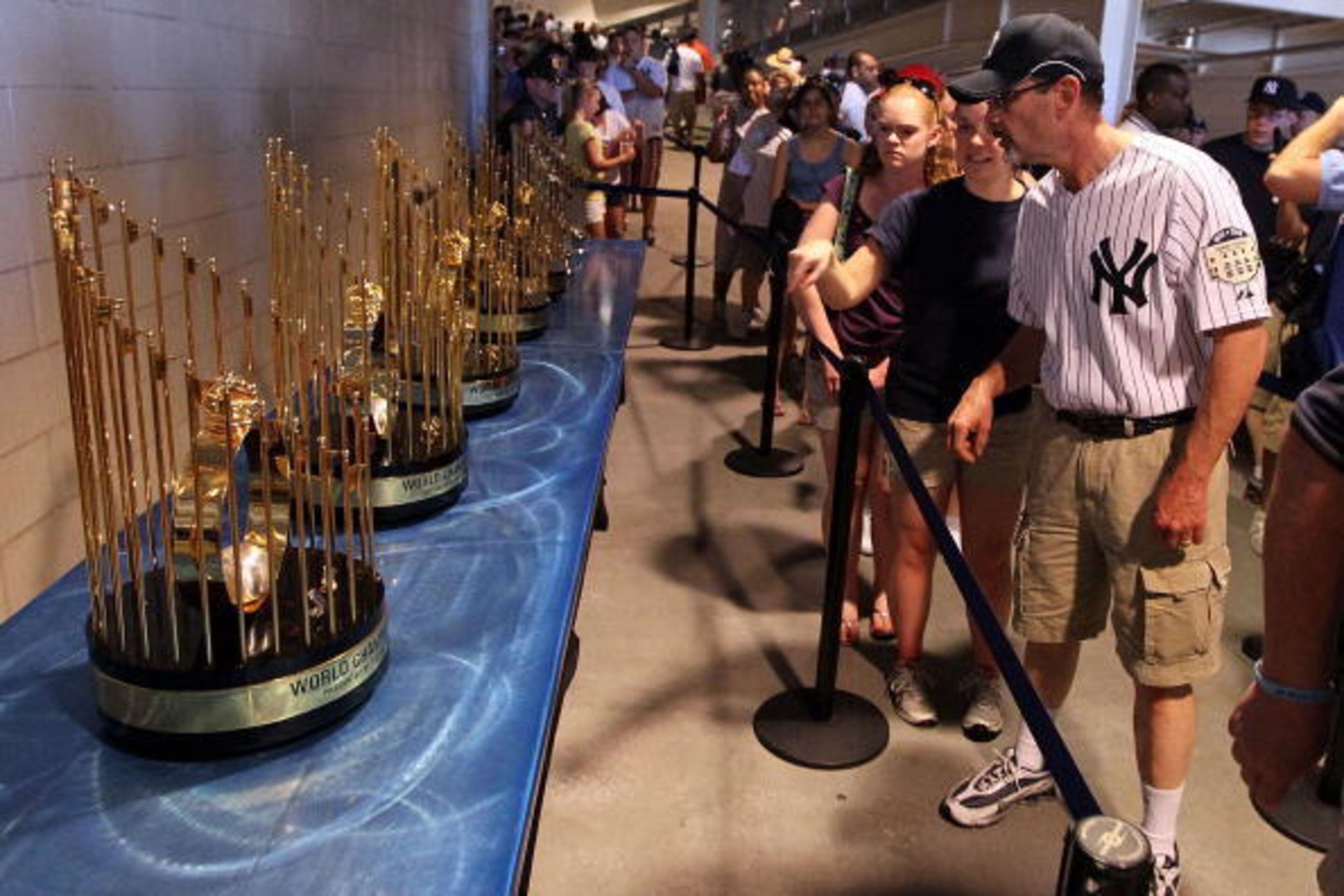 NEW YORK - JULY 04:  Fans view the seven World Series championship trophies won by the New York Yankees under the ownership of George Steinbrenner prior to the game against the Toronto Blue Jays on July 4, 2010 at Yankee Stadium in the Bronx borough of Ne