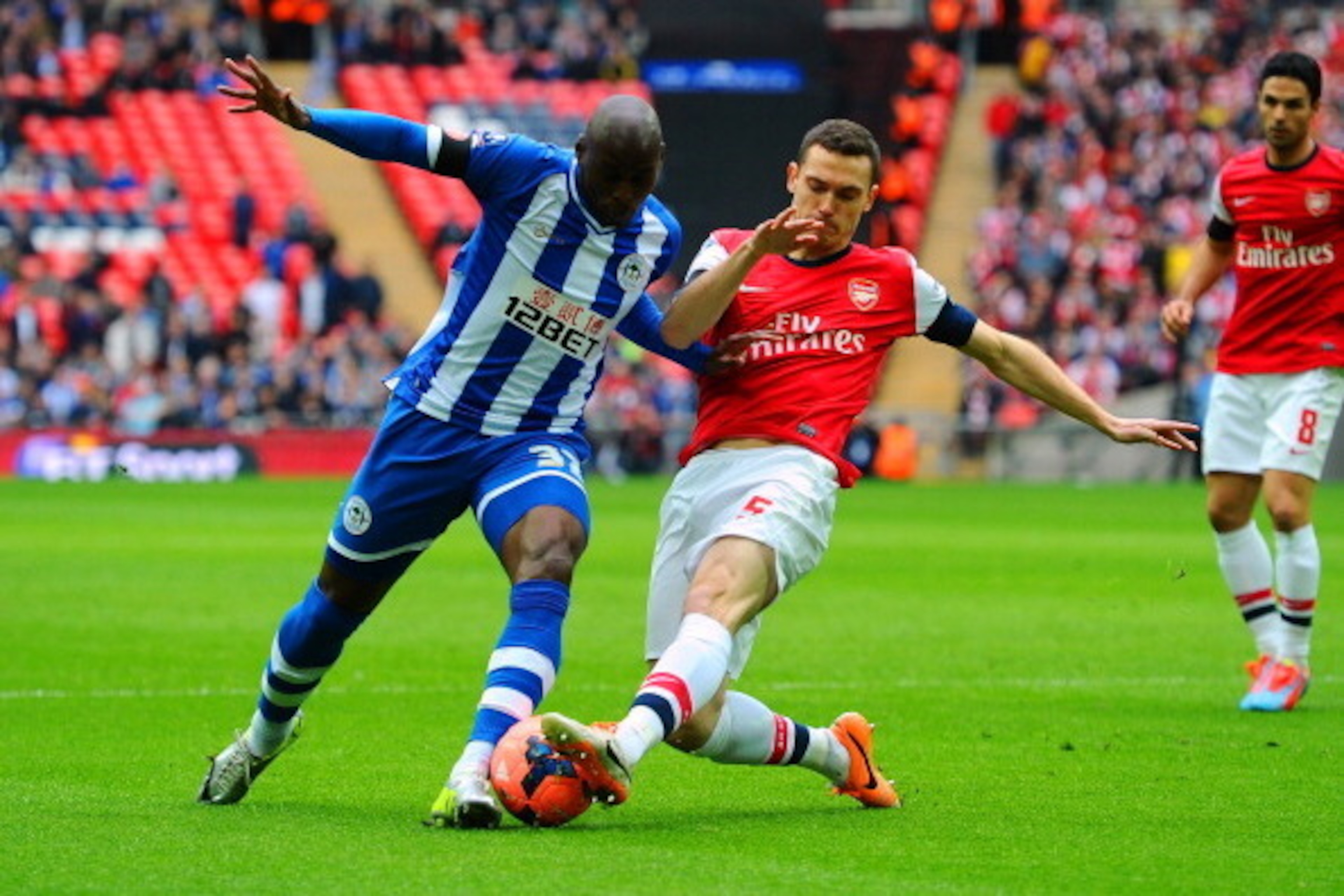 LONDON, ENGLAND - APRIL 12:  Marc-Antoine Fortune of Wigan Athletic is tackled by Thomas Vermaelen of Arsenal during the FA Cup Semi-Final match between Wigan Athletic and Arsenal at Wembley Stadium on April 12, 2014 in London, England.  (Photo by Mike He