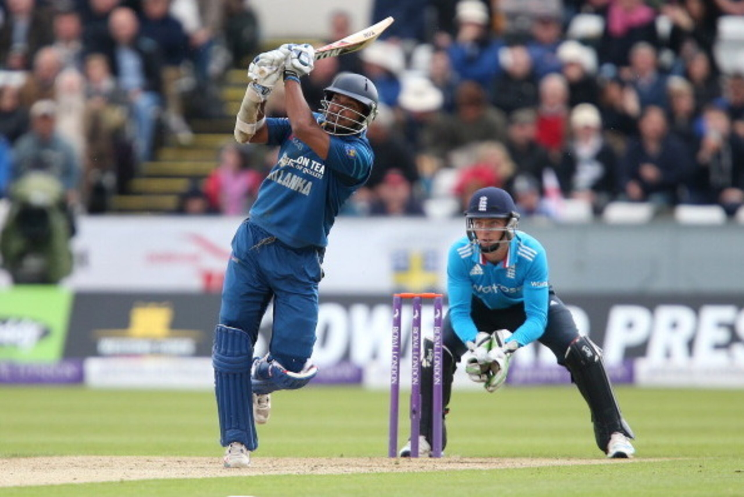 CHESTER-LE-STREET, ENGLAND - MAY 25:  Kumar Sangakkara of Sri Lanka hits out with Jos Buttler of England looking on during the 2nd Royal London One Day International match between England and Sri Lanka at The Riverside on May 25, 2014 in Chester-le-Street