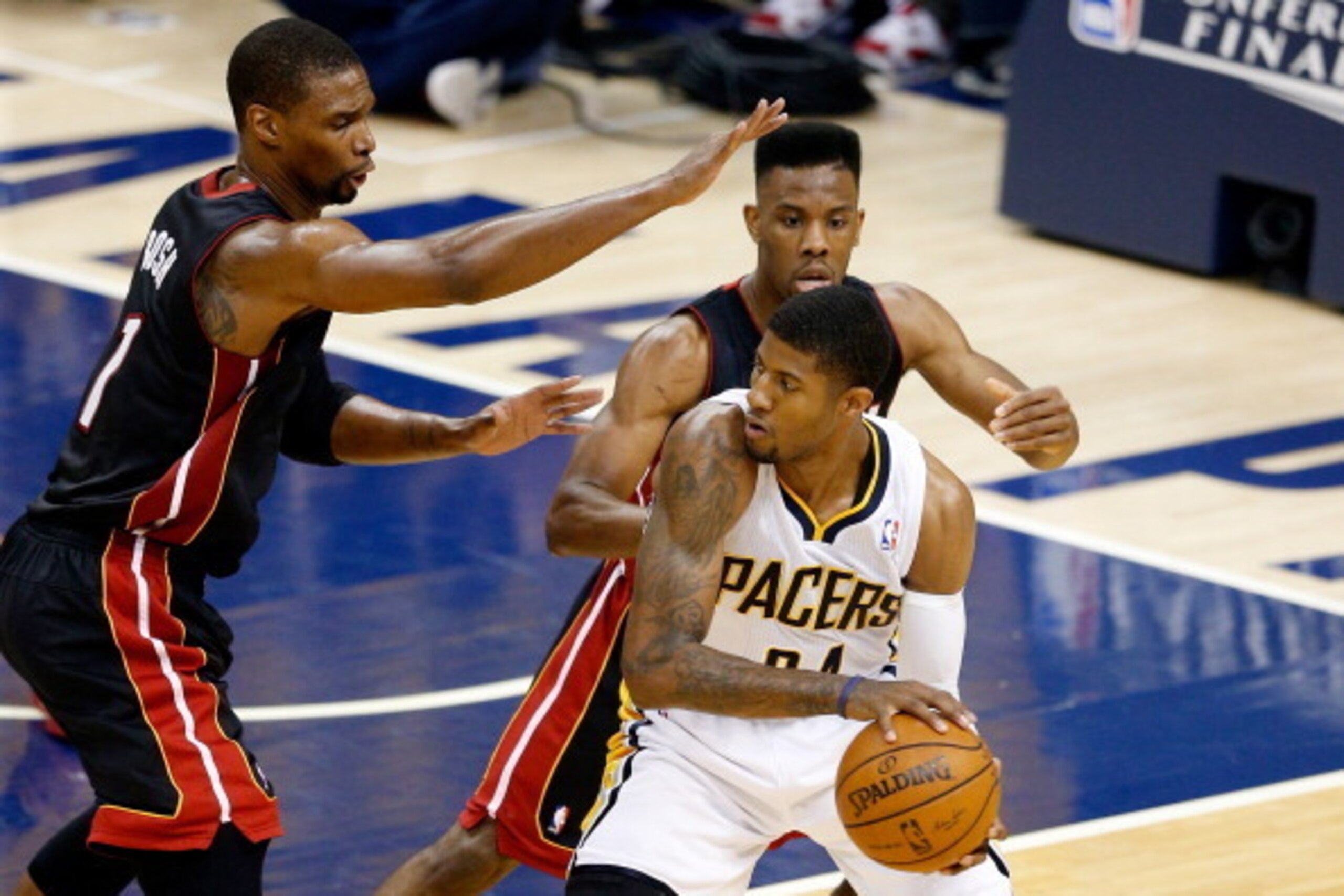 INDIANAPOLIS, IN - MAY 28:  Paul George #24 of the Indiana Pacers looks to pass as Chris Bosh #1 and Norris Cole #30 of the Miami Heat defend during Game Five of the Eastern Conference Finals of the 2014 NBA Playoffs at Bankers Life Fieldhouse on May 28, 