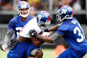 Jul 28, 2012; Albany, NY, USA; New York Giants running back David Wilson (34) carries the ball against defensive back Will Hill (38) and defensive back Antwaun Molden (22) during training camp at University Field at SUNY Albany.  Mandatory Credit: Mark L.