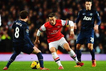 LONDON, ENGLAND - FEBRUARY 12:  Mesut Ozil (C) of Arsenal takes on Juan Mata (L) of Manchester United during the Barclays Premier League match between Arsenal and Manchester United at the Emirates Stadium on February 12, 2014 in London, England.  (Photo b