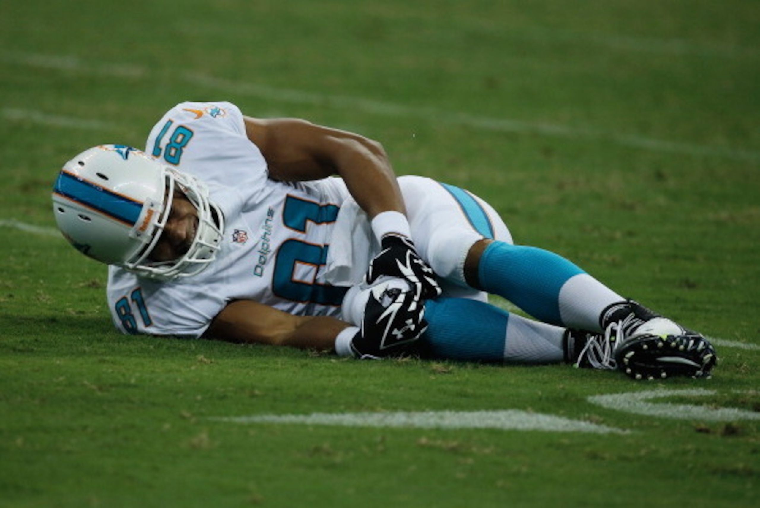 HOUSTON, TX - AUGUST 17:  Dustin Keller#81 of the Miami Dolphins sits on the f1eld after a rough tackle in the first half against the Houston Texans during a preseaon game at Reliant Stadium on August 17, 2013 in Houston, Texas.  (Photo by Scott Halleran/