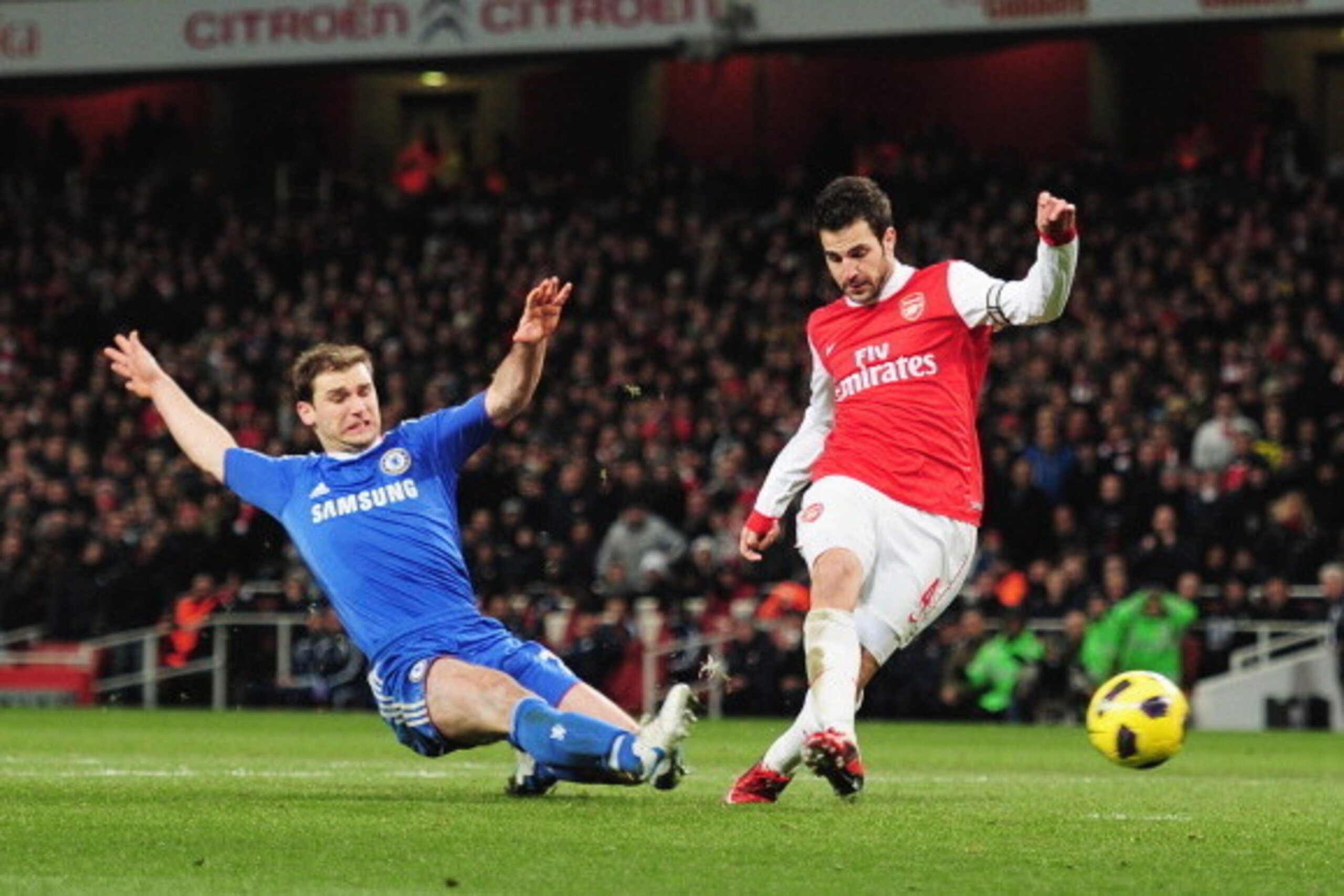 LONDON, ENGLAND - DECEMBER 27:  Cesc Fabregas of Arsenal shoots to score Arsenal's second goal despite a challenge by Branislav Ivanovic of Chelsea during the Barclays Premier League match between Arsenal and Chelsea at the Emirates Stadium on December 27