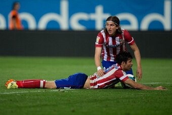 MADRID, SPAIN - APRIL 18: Filipe Luis (R) of Atletico de Madrid assists his teammate Diego Costa (L) after being tackled by Cristian Sapunaru of Elche FC  during the La Liga match between Club Atletico de Madrid and Elche FC at Vicente Calderon Stadium on