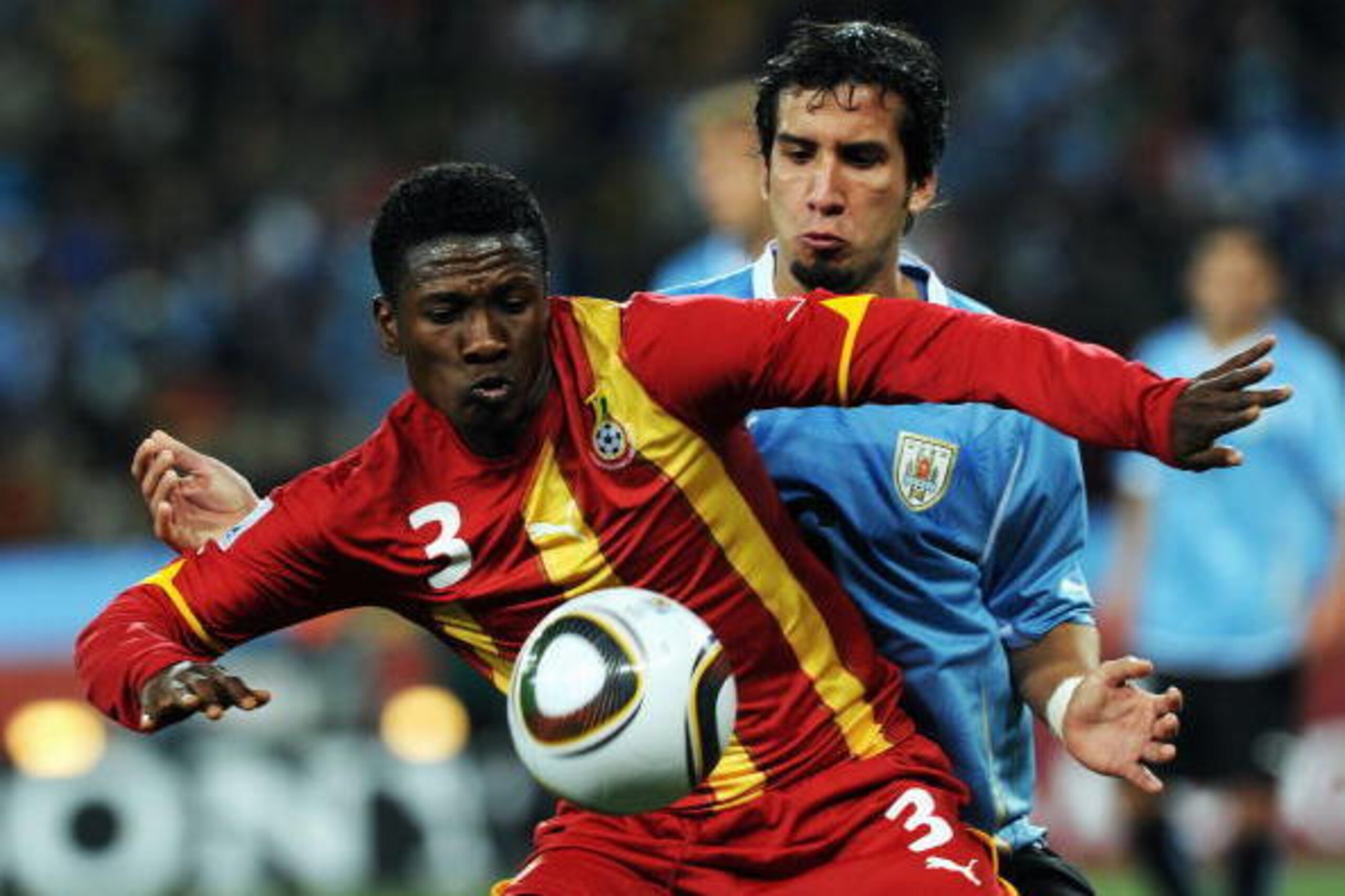 JOHANNESBURG, SOUTH AFRICA - JULY 02:  Jorge Fucile of Uruguay watches Asamoah Gyan of Ghana during the 2010 FIFA World Cup South Africa Quarter Final match between Uruguay and Ghana at the Soccer City stadium on July 2, 2010 in Johannesburg, South Africa
