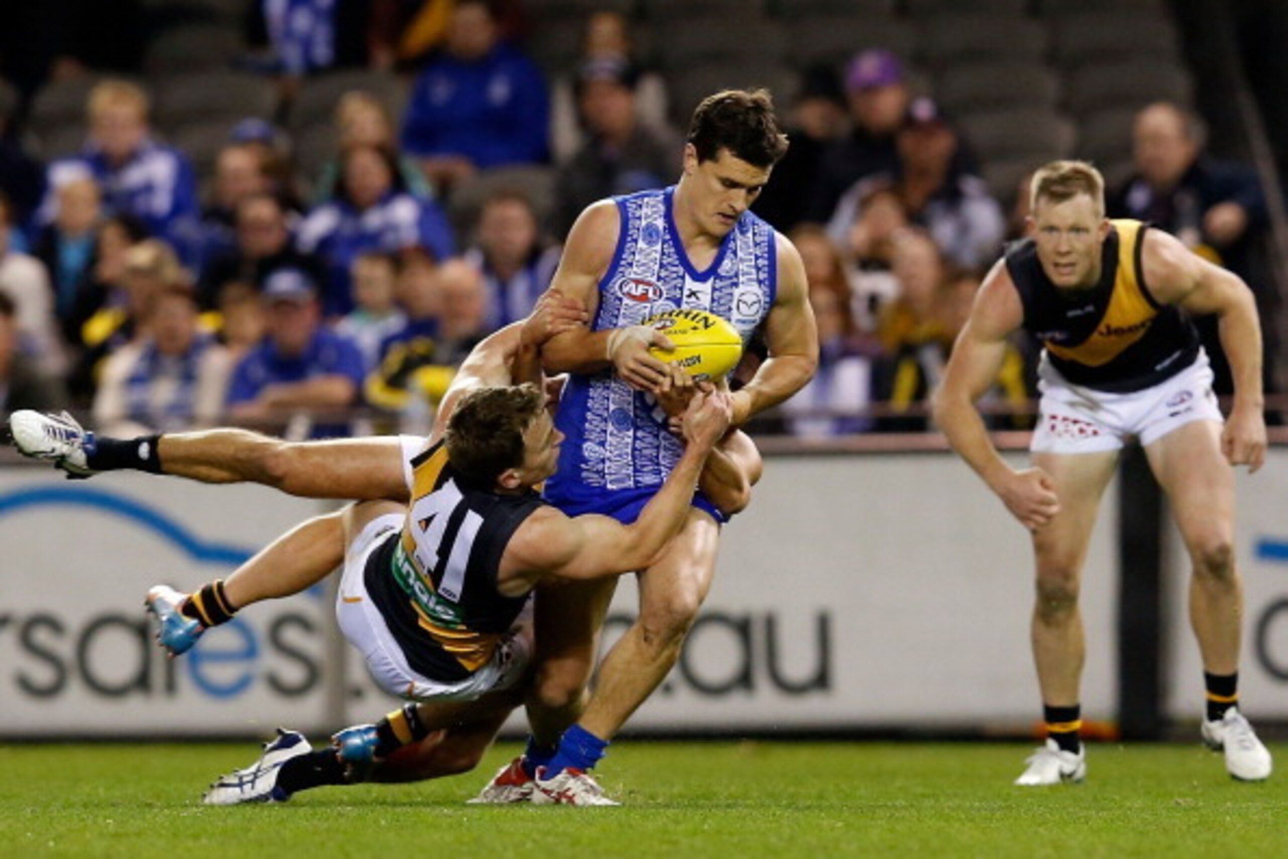 MELBOURNE, AUSTRALIA - JUNE 08:  Scott Thompson of the Kangaroos is tackled by Nathan Foley of the Tigers during the round 12 AFL match between the North Melbourne Kangaroos and the Richmond Tigers at Etihad Stadium on June 8, 2014 in Melbourne, Australia