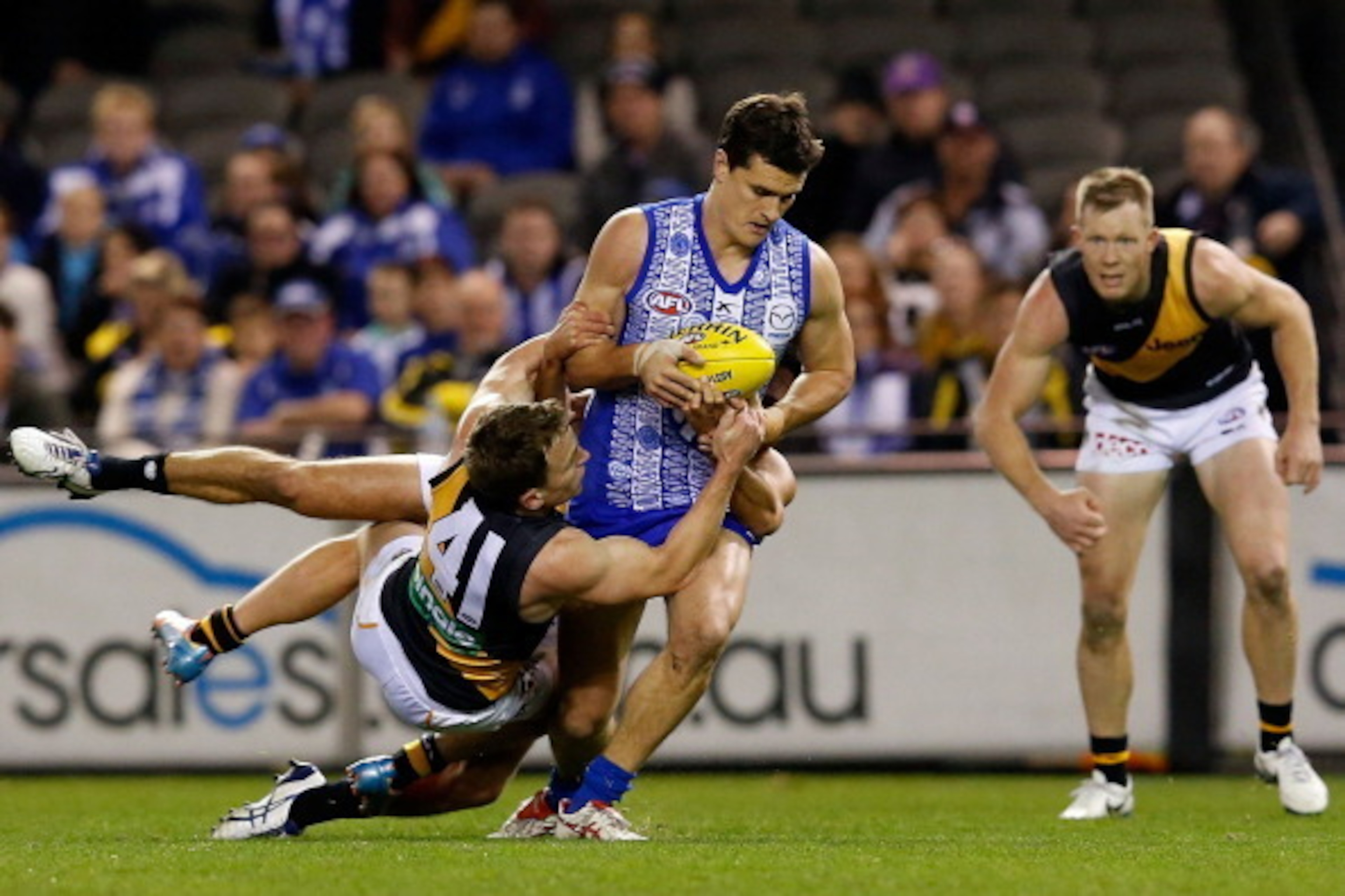 MELBOURNE, AUSTRALIA - JUNE 08:  Scott Thompson of the Kangaroos is tackled by Nathan Foley of the Tigers during the round 12 AFL match between the North Melbourne Kangaroos and the Richmond Tigers at Etihad Stadium on June 8, 2014 in Melbourne, Australia