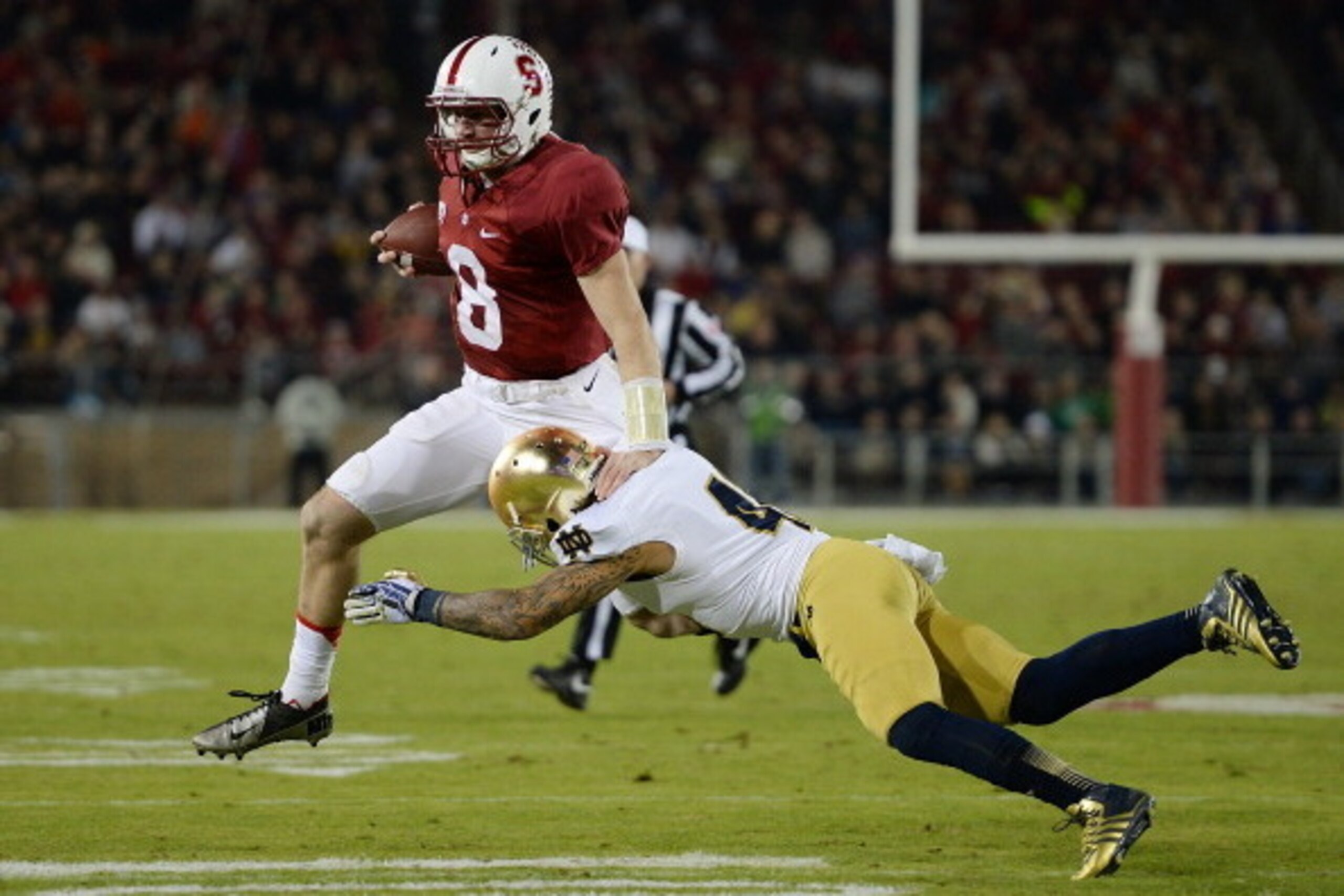 PALO ALTO, CA - NOVEMBER 30:  Kevin Hogan #8 of the Stanford Cardinal gets tackled short of a first down by Matthias Farley #41 of the Notre Dame Fighting Irish during the third quarter at Stanford Stadium on November 30, 2013 in Palo Alto, California.  (