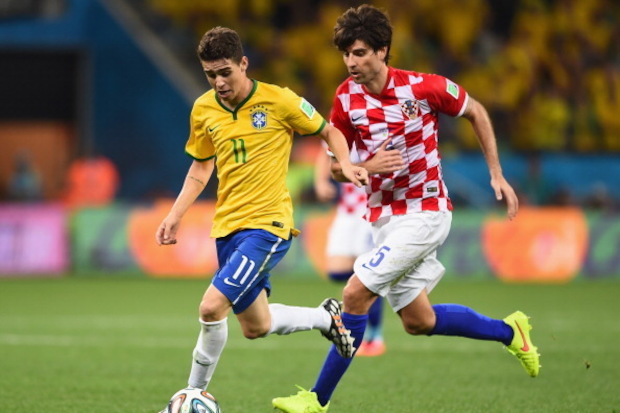 SAO PAULO, BRAZIL - JUNE 12:  Oscar of Brazil dribbles toward the goal past Vedran Corluka of Croatia during the 2014 FIFA World Cup Brazil Group A match between Brazil and Croatia at Arena de Sao Paulo on June 12, 2014 in Sao Paulo, Brazil.  (Photo by Bu