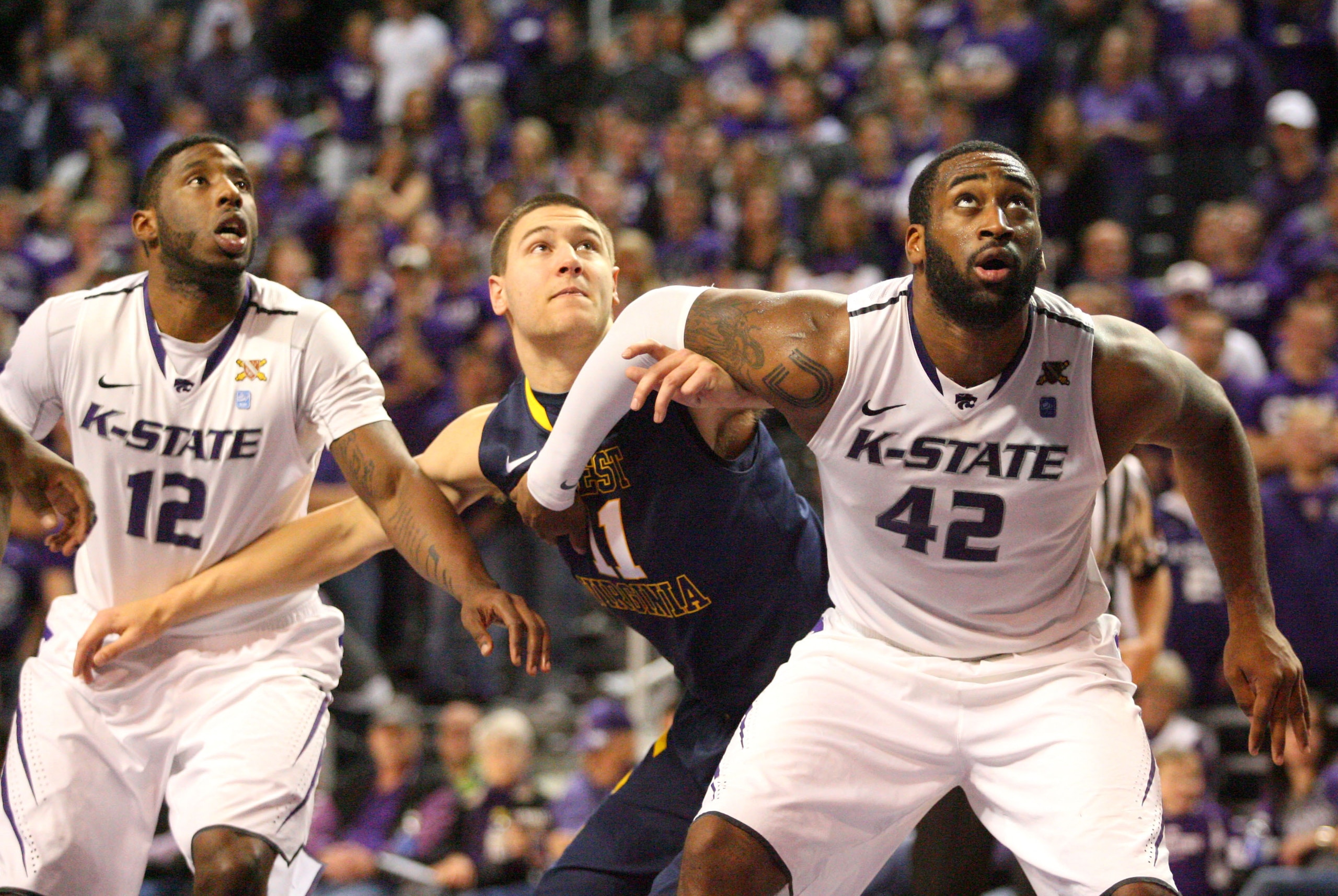Jan 18, 2014; Manhattan, KS, USA; West Virginia Mountaineers forward Nathan Adrian (11) is blocked out by Kansas State Wildcats forward Thomas Gipson (42) and guard Omari Lawrence (12) during the Mountaineers' 78-56 loss at Fred Bramlage Coliseum. Mandato
