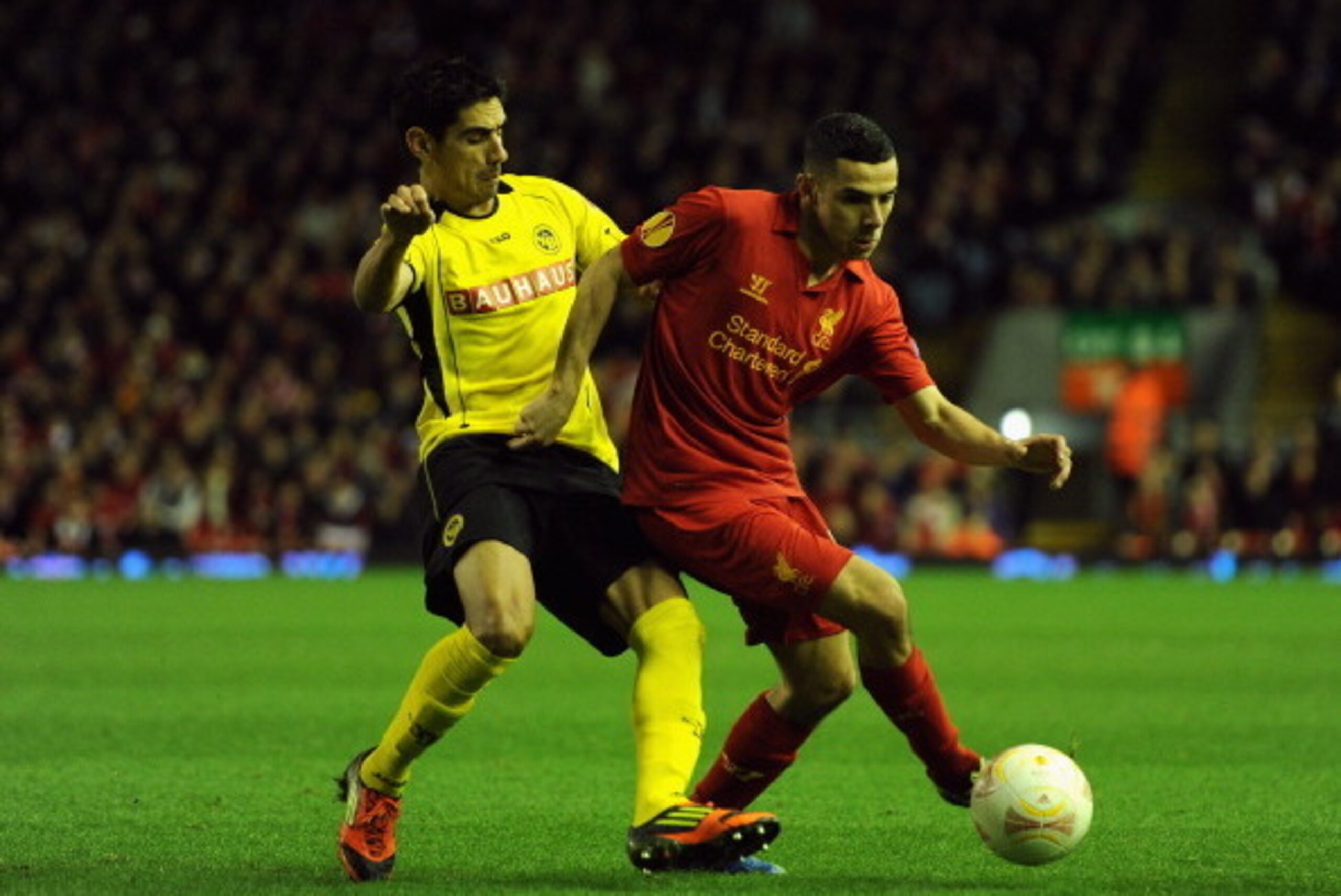 LIVERPOOL, ENGLAND - NOVEMBER 22:  Gonzalo Zarate of Young Boys competes with Oussama Assaidi of Liverpool during the UEFA Europa League Group A match between Liverpool FC and BSC Young Boys at Anfield on November 22, 2012 in Liverpool, England.  (Photo b