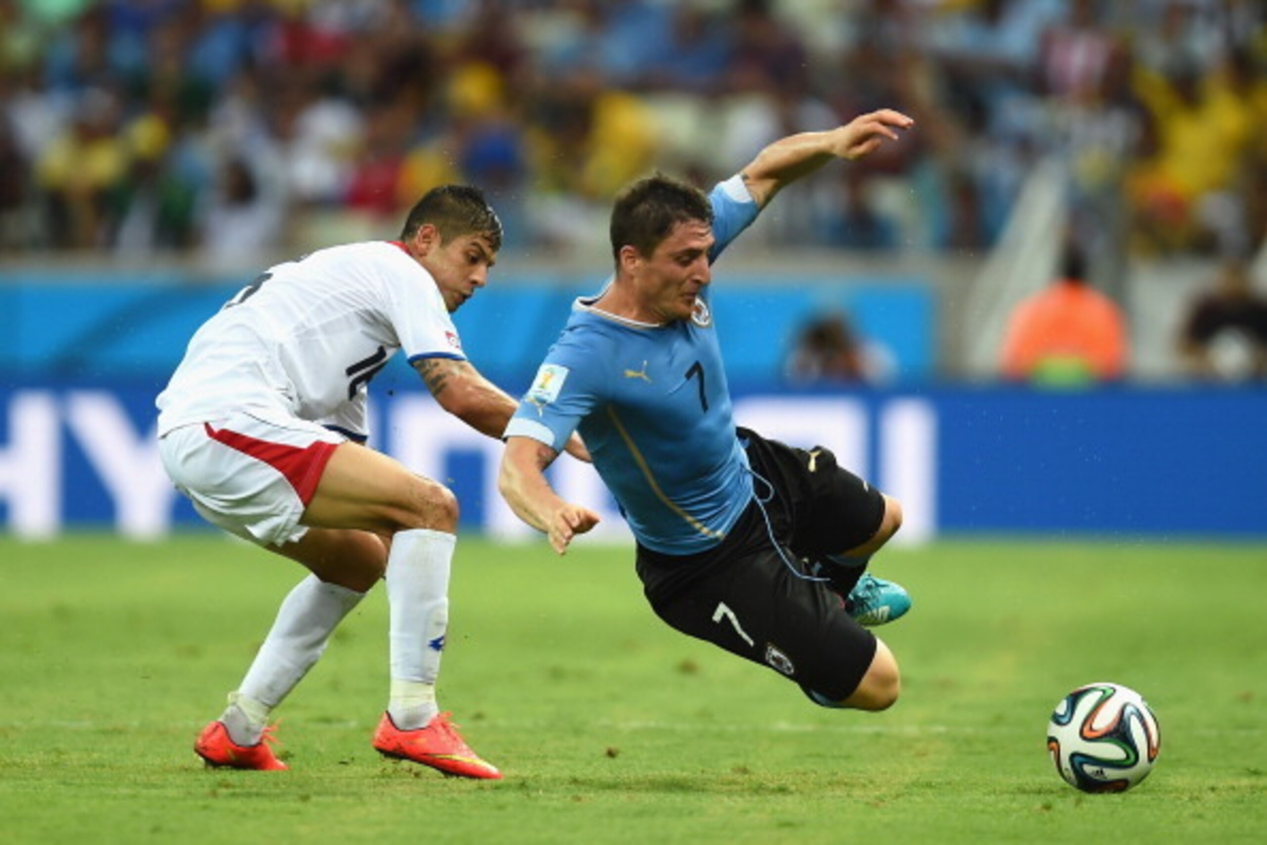 FORTALEZA, BRAZIL - JUNE 14: Cristian Rodriguez of Uruguay falls after a challenge by Cristian Gamboa of Costa Rica during the 2014 FIFA World Cup Brazil Group D match between Uruguay and Costa Rica at Castelao on June 14, 2014 in Fortaleza, Brazil.  (Pho