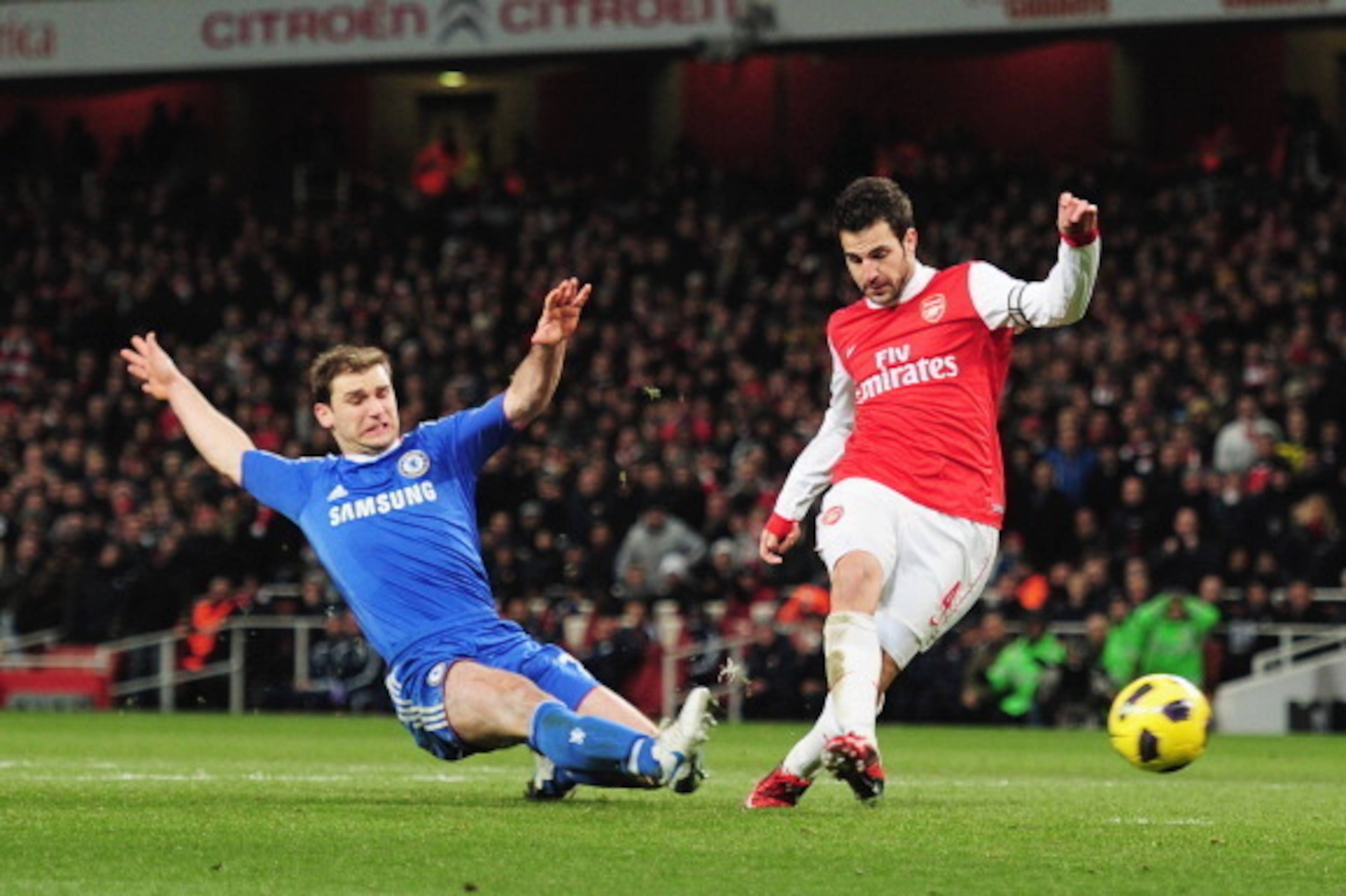 LONDON, ENGLAND - DECEMBER 27:  Cesc Fabregas of Arsenal shoots to score Arsenal's second goal despite a challenge by Branislav Ivanovic of Chelsea during the Barclays Premier League match between Arsenal and Chelsea at the Emirates Stadium on December 27