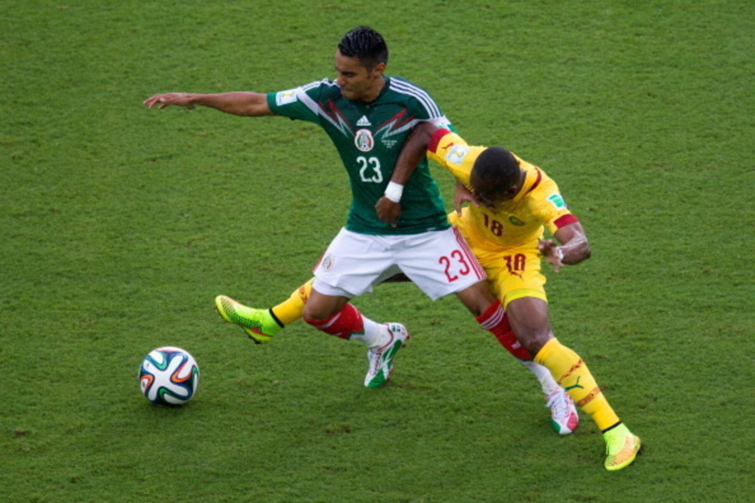 NATAL, BRAZIL - JUNE 13: Enoh Eyong of Cameroon challenges Jose Juan Vazquez of Mexico in the first half during the 2014 FIFA World Cup Brazil Group A match between Mexico and Cameroon at Estadio das Dunas on June 13, 2014 in Natal, Brazil.  (Photo by Mig