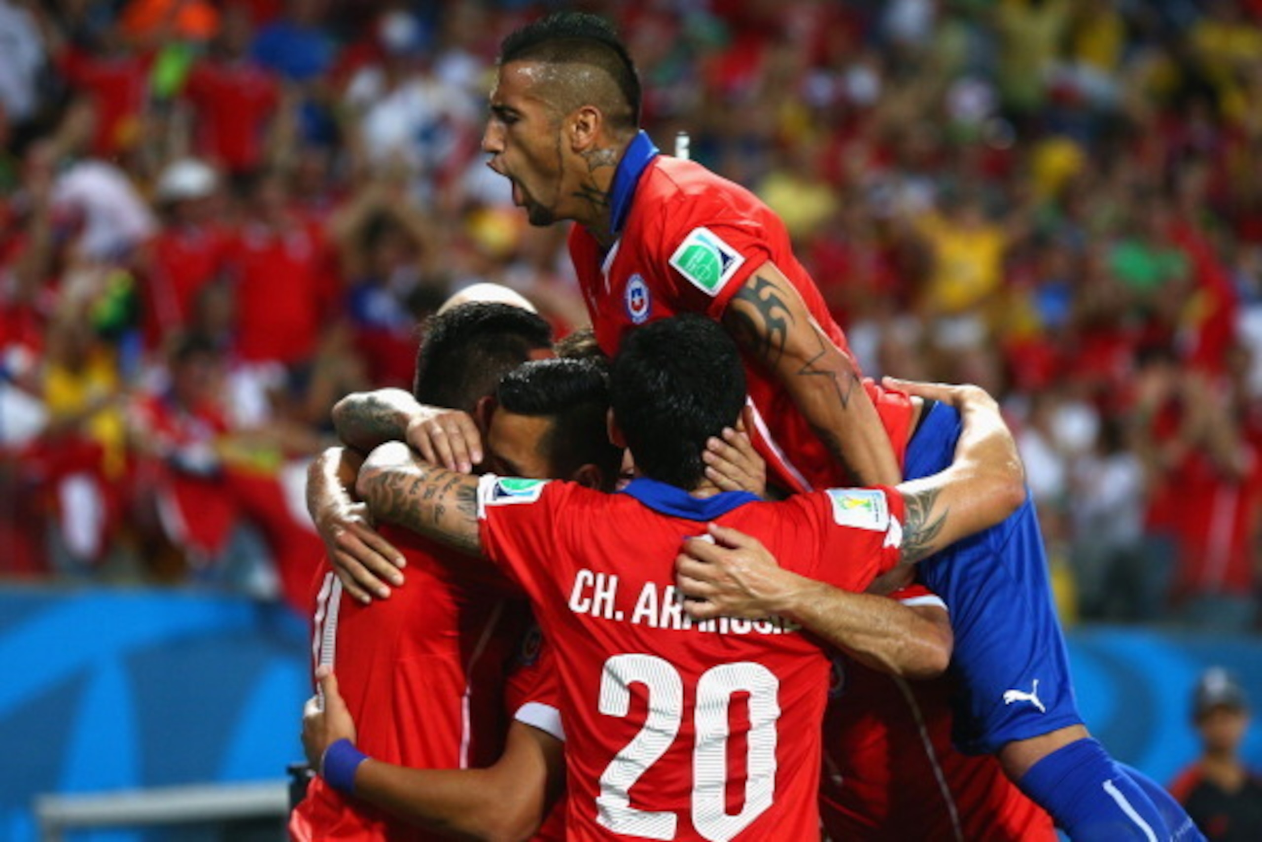 CUIABA, BRAZIL - JUNE 13: Arturo Vidal of Chile jumps on a group of teammates celebrating their first goal by Alexis Sanchez (C) during the 2014 FIFA World Cup Brazil Group B match between Chile and Australia at Arena Pantanal on June 13, 2014 in Cuiaba, 