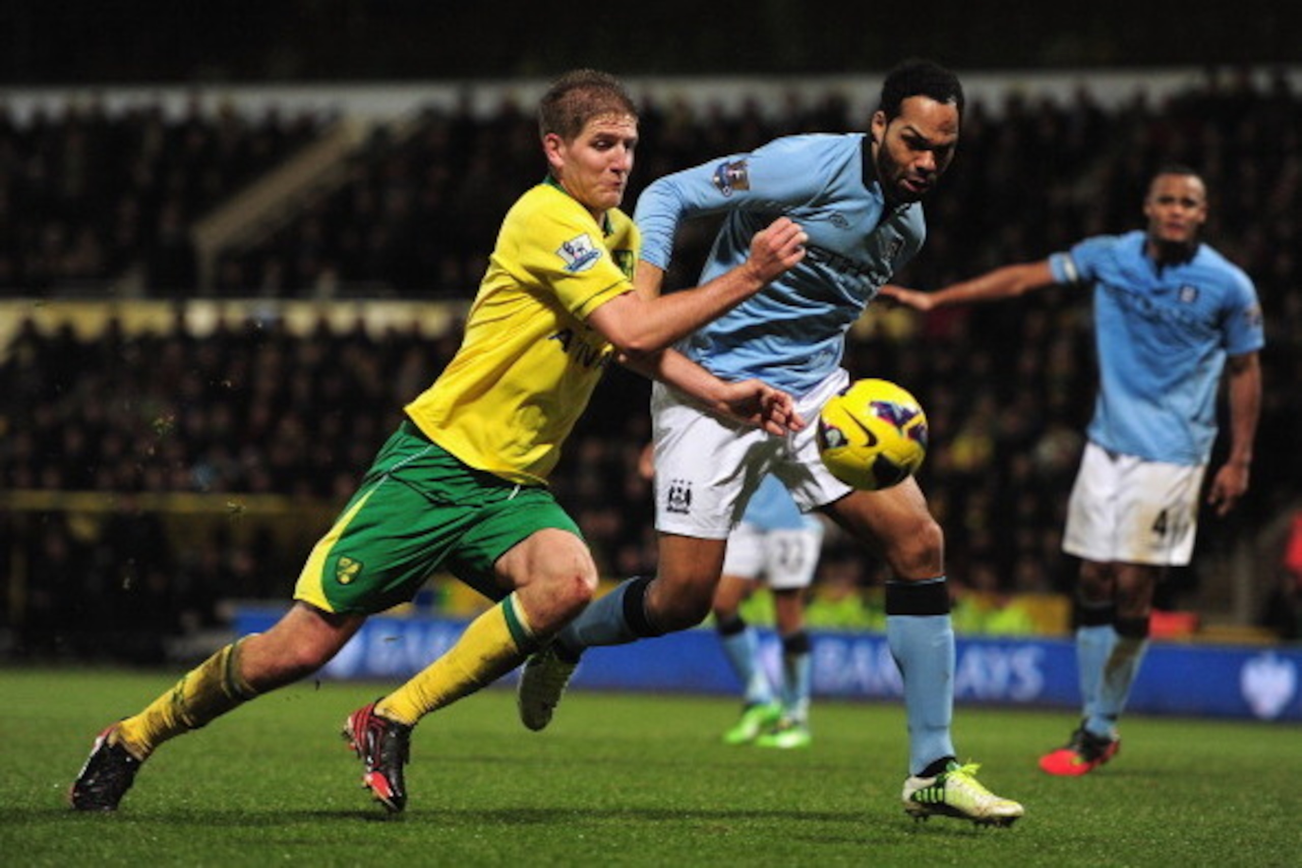 NORWICH, ENGLAND - DECEMBER 29:  Michael Turner of Norwich City and Joleon Lescott of Manchester City tussle for the ball during the Barclays Premier League match between Norwich City and Manchester City at Carrow Road on December 29, 2012 in Norwich, Eng