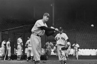 BOSTON, MA - CIRCA 1945:  (UNDATED FILE PHOTO)  Baseball legend Ted Williams (1919 - 2002) of the Boston Red Sox swings a bat at a ball during a pre-game practice as Walter 'Smokey' Baker, the 13-year-old son of Red Sox pitching coach Del Baker (1892 - 19