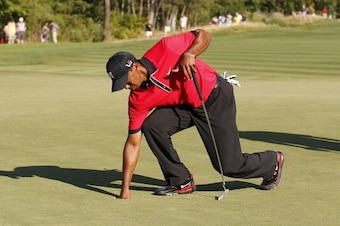 JERSEY CITY, NJ - AUGUST 25:  Tiger Woods carefully bends down to remove his ball from the 15th hole after injuring his back during the fourth round of The Barclays held at Liberty National Golf Club on August 25, 2013 in Jersey City, New Jersey.  (Photo 