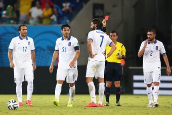 NATAL, BRAZIL - JUNE 19:  Konstantinos Katsouranis of Greece (2nd L) is shown a red card after receiving his second yellow by referee Joel Aguilar during the 2014 FIFA World Cup Brazil Group  C match between Japan and Greece at Estadio das Dunas on June 1