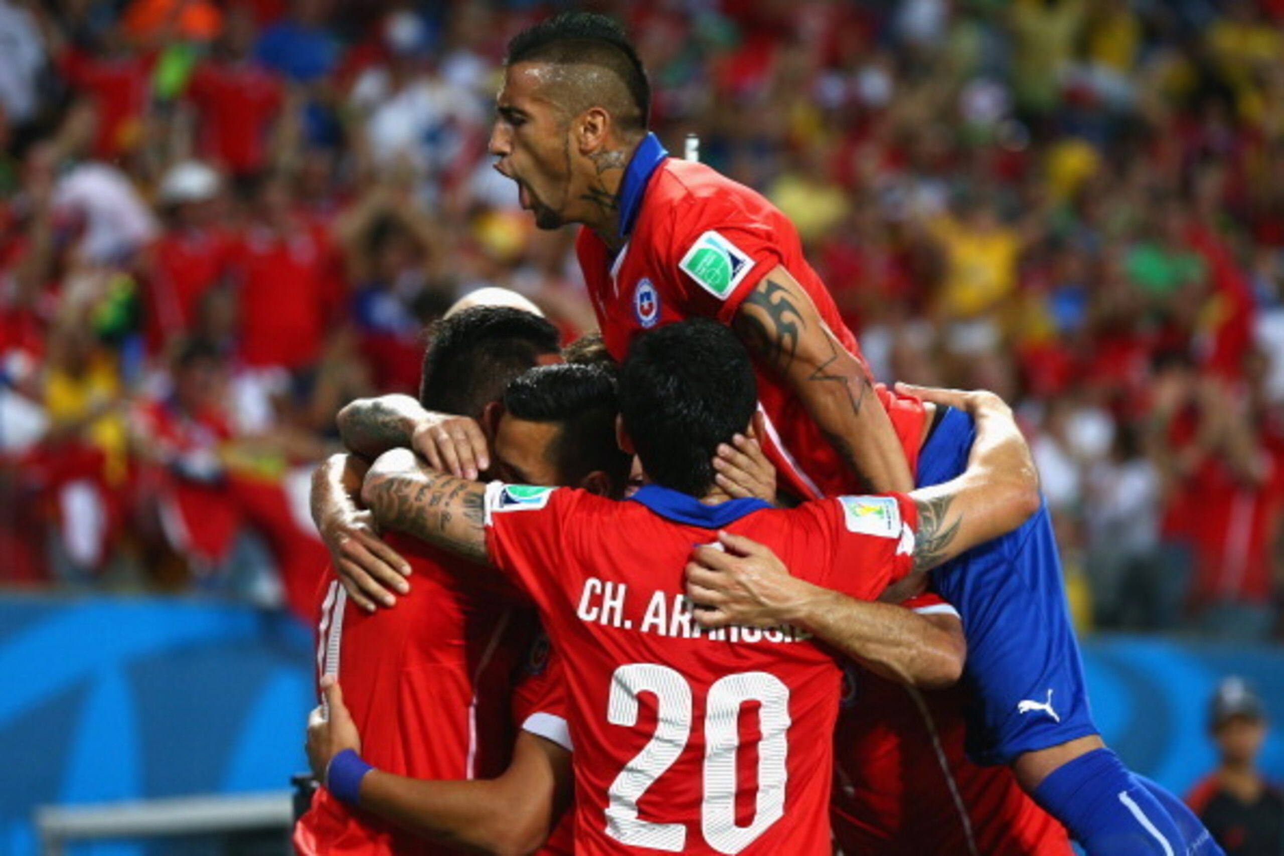 CUIABA, BRAZIL - JUNE 13: Arturo Vidal of Chile jumps on a group of teammates celebrating their first goal by Alexis Sanchez (C) during the 2014 FIFA World Cup Brazil Group B match between Chile and Australia at Arena Pantanal on June 13, 2014 in Cuiaba, 