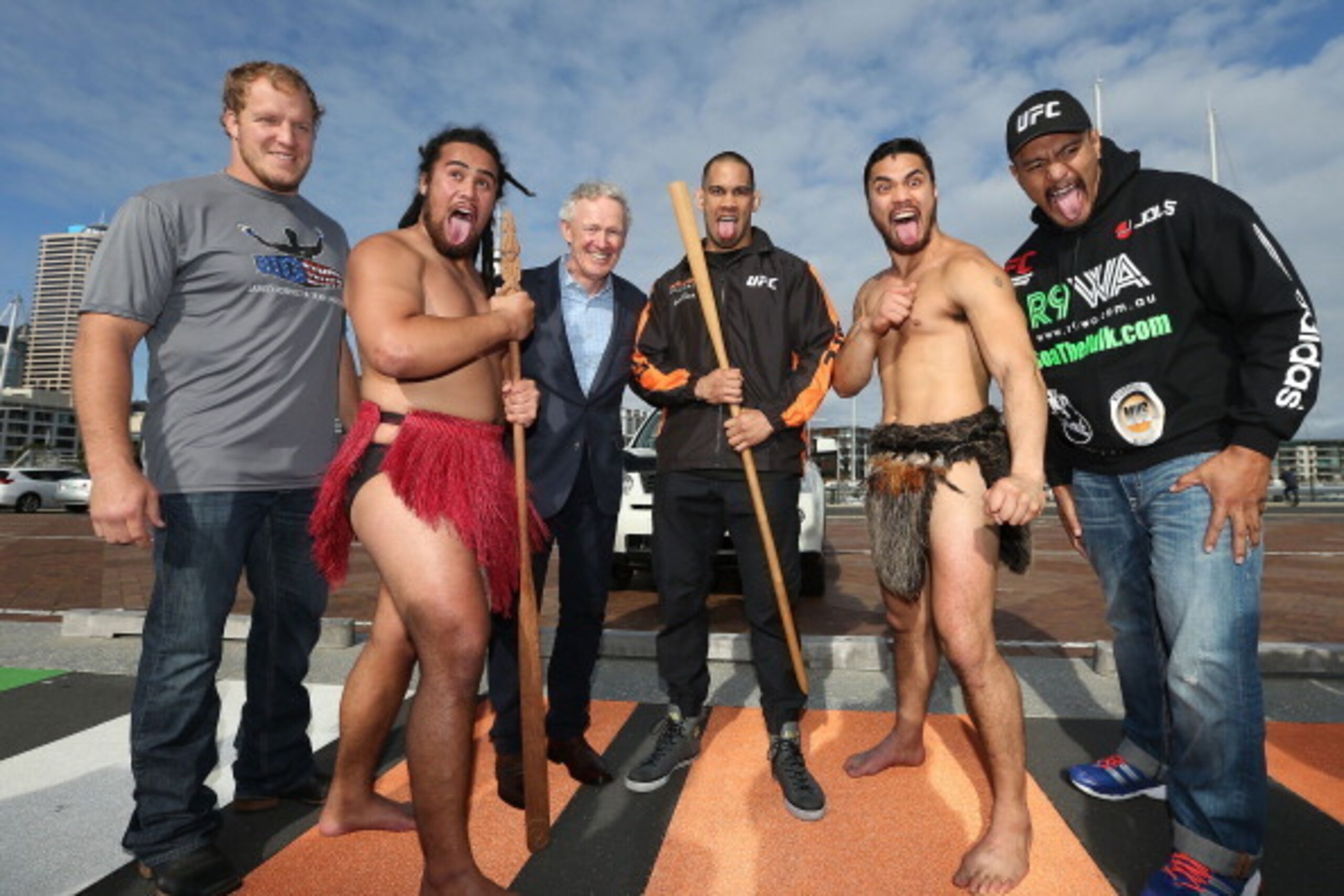 AUCKLAND, NEW ZEALAND - JUNE 24:  UFC Fighters Jared Rosholt of USA (L) James Te Huna (C) and Soa Palelei of Australia (R) join Maori cultural performers Edz Eramiha (R) and Iwi Matthews (L) with UFC Managing Director Tom Wright (in suit) after a traditio