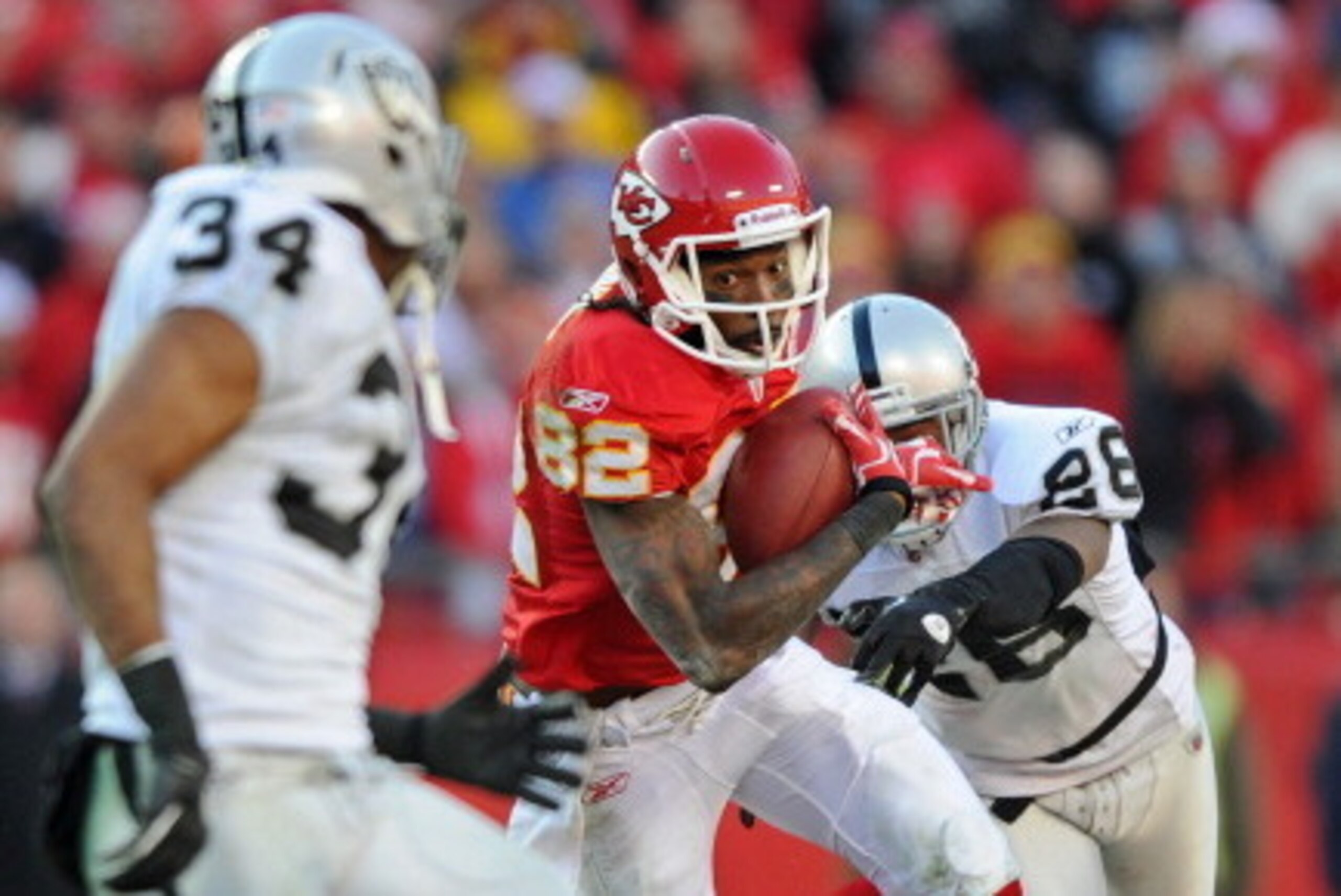 KANSAS CITY, MO - DECEMBER 24:  Wide receiver Dwayne Bowe #82 of the Kansas City Chiefs catches a pass between defenders Stanford Routt #26 and Mike Mitchell #34 of the Oakland Raiders during the second half on December 24, 2011 at Arrowhead Stadium in Ka