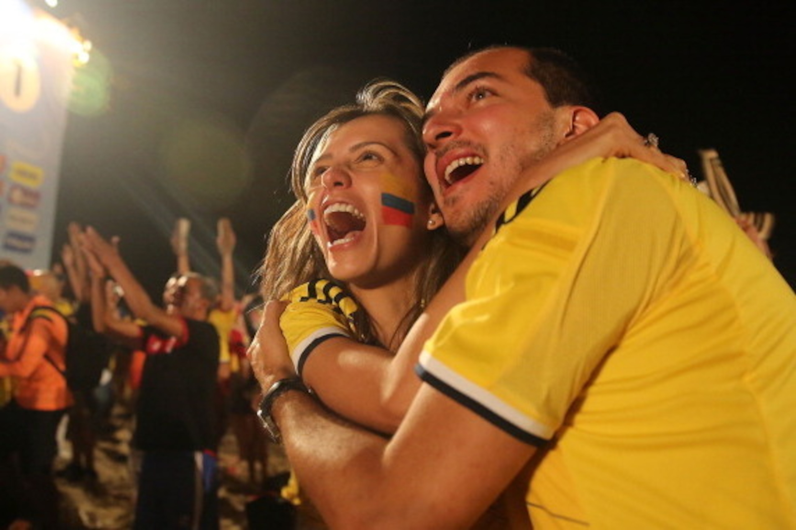 RIO DE JANEIRO, BRAZIL - JUNE 24:  Colombia supporters embrace and celebrate after they defeated Japan while watching at the FIFA Fan Fest on Copacabana Beach on June 24, 2014 in Rio de Janeiro, Brazil.  (Photo by Mario Tama/Getty Images)