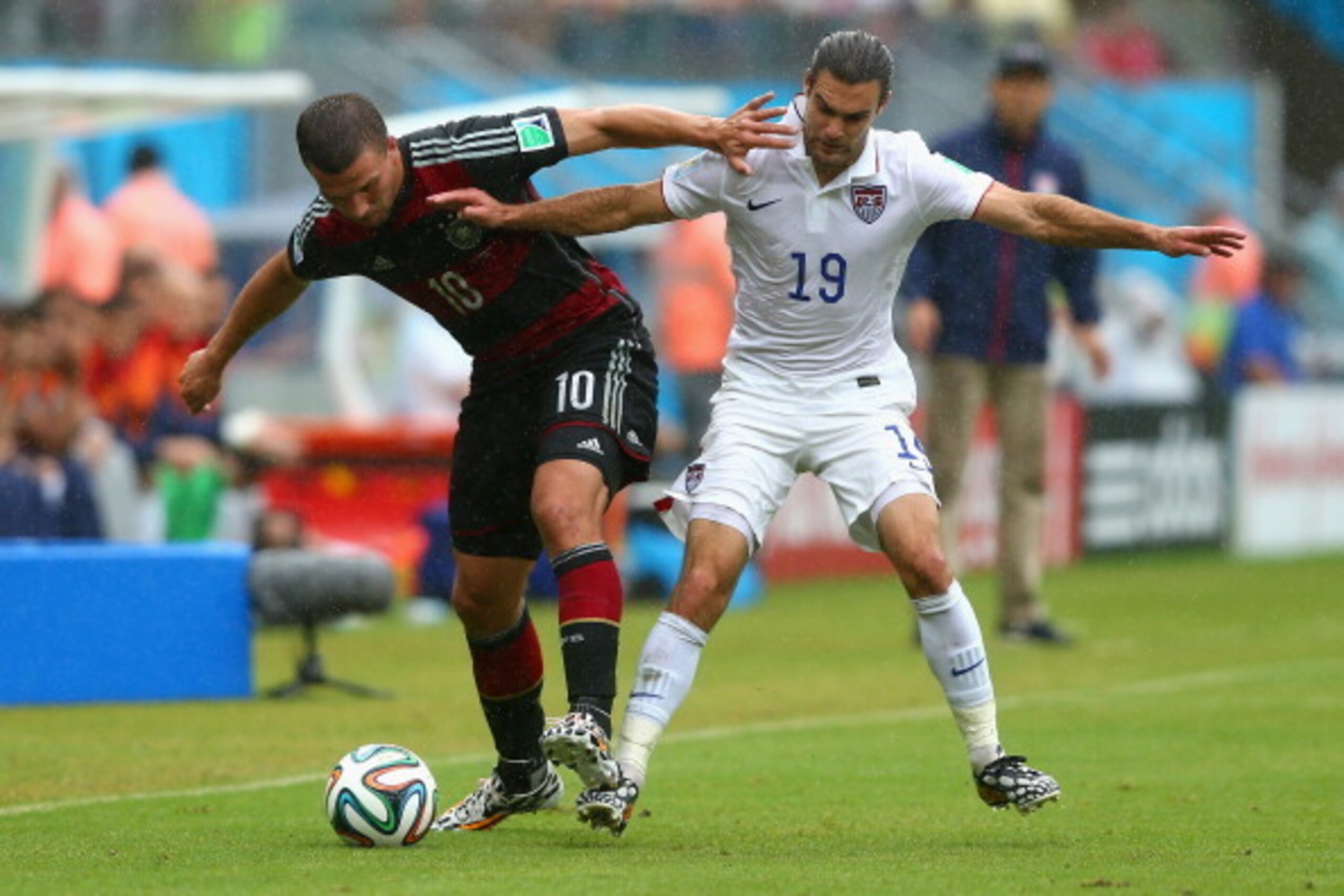 RECIFE, BRAZIL - JUNE 26: Lukas Podolski of Germany is challenged by Graham Zusi of the United States during the 2014 FIFA World Cup Brazil group G match between the United States and Germany at Arena Pernambuco on June 26, 2014 in Recife, Brazil.  (Photo