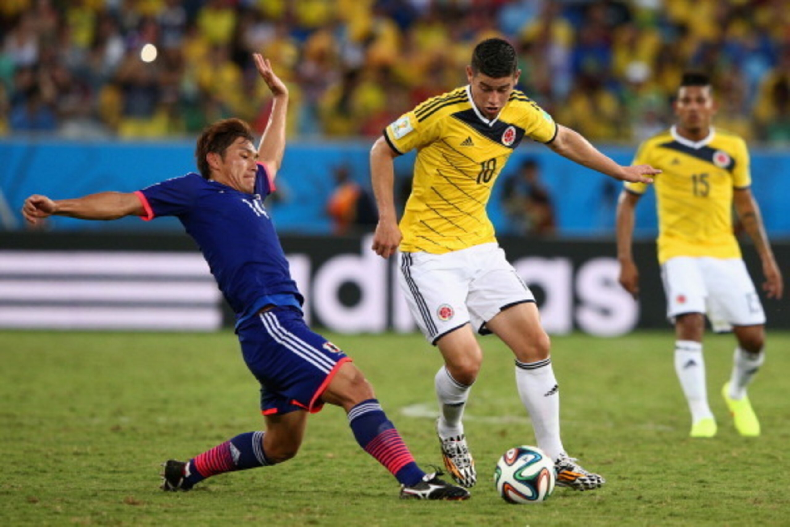 CUIABA, BRAZIL - JUNE 24:  Toshihiro Aoyama of Japan tackles James Rodriguez of Colombia during the 2014 FIFA World Cup Brazil Group C match between Japan and Colombia at Arena Pantanal on June 24, 2014 in Cuiaba, Brazil.  (Photo by Adam Pretty/Getty Imag
