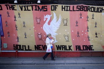 LIVERPOOL, ENGLAND - APRIL 15:  A woman walks past a Hillsborough tribute banner as fans arrive in Anfield for a memorial service marking the 25th anniversary of the Hillsborough Disaster at Anfield stadium on April 15, 2014 in Liverpool, England. Thousan