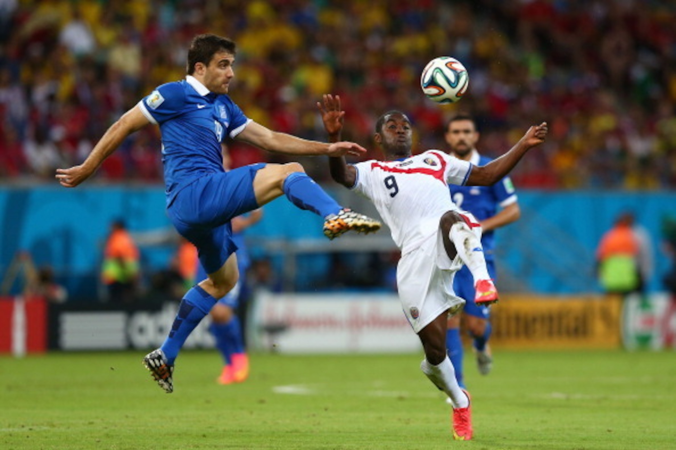RECIFE, BRAZIL - JUNE 29:  Sokratis Papastathopoulos of Greece challenges Joel Campbell of Costa Rica during the 2014 FIFA World Cup Brazil Round of 16 match between Costa Rica and Greece at Arena Pernambuco on June 29, 2014 in Recife, Brazil.  (Photo by 