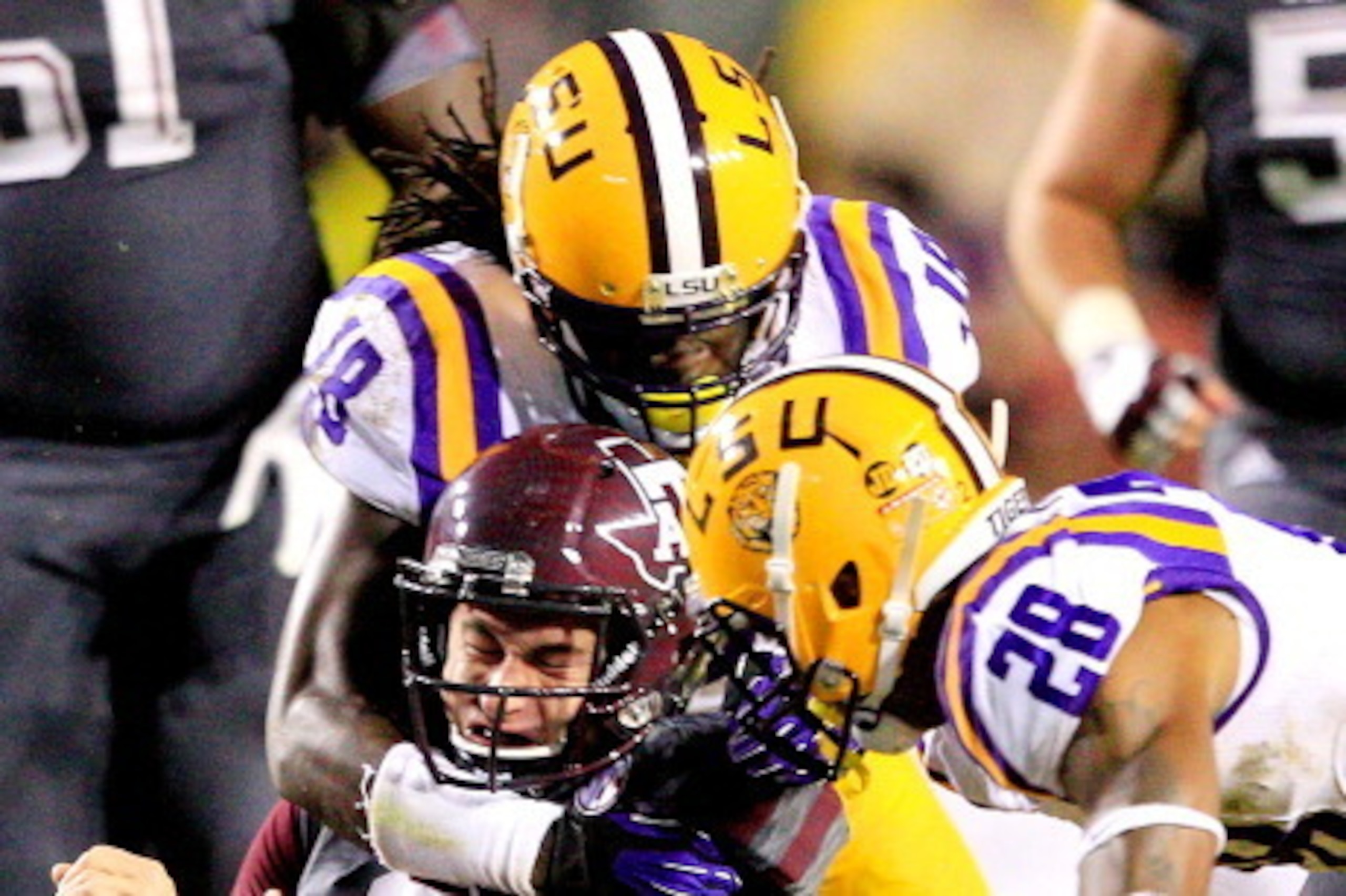 BATON ROUGE, LA - NOVEMBER 23:  Quarterback Johnny Manziel #2 of the Texas A&M Aggies is tackled by linebacker Lamin Barrow #18 and cornerback Jalen Mills #28 of the LSU Tigers at Tiger Stadium on November 23, 2013 in Baton Rouge, Louisiana.  (Photo by Se