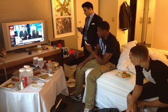 LaVine (right) checks in on the latest draft news on ESPN, while his agent, Nima Namakian (left), and best friend, Perrion Callandret, provide support in his hotel room.